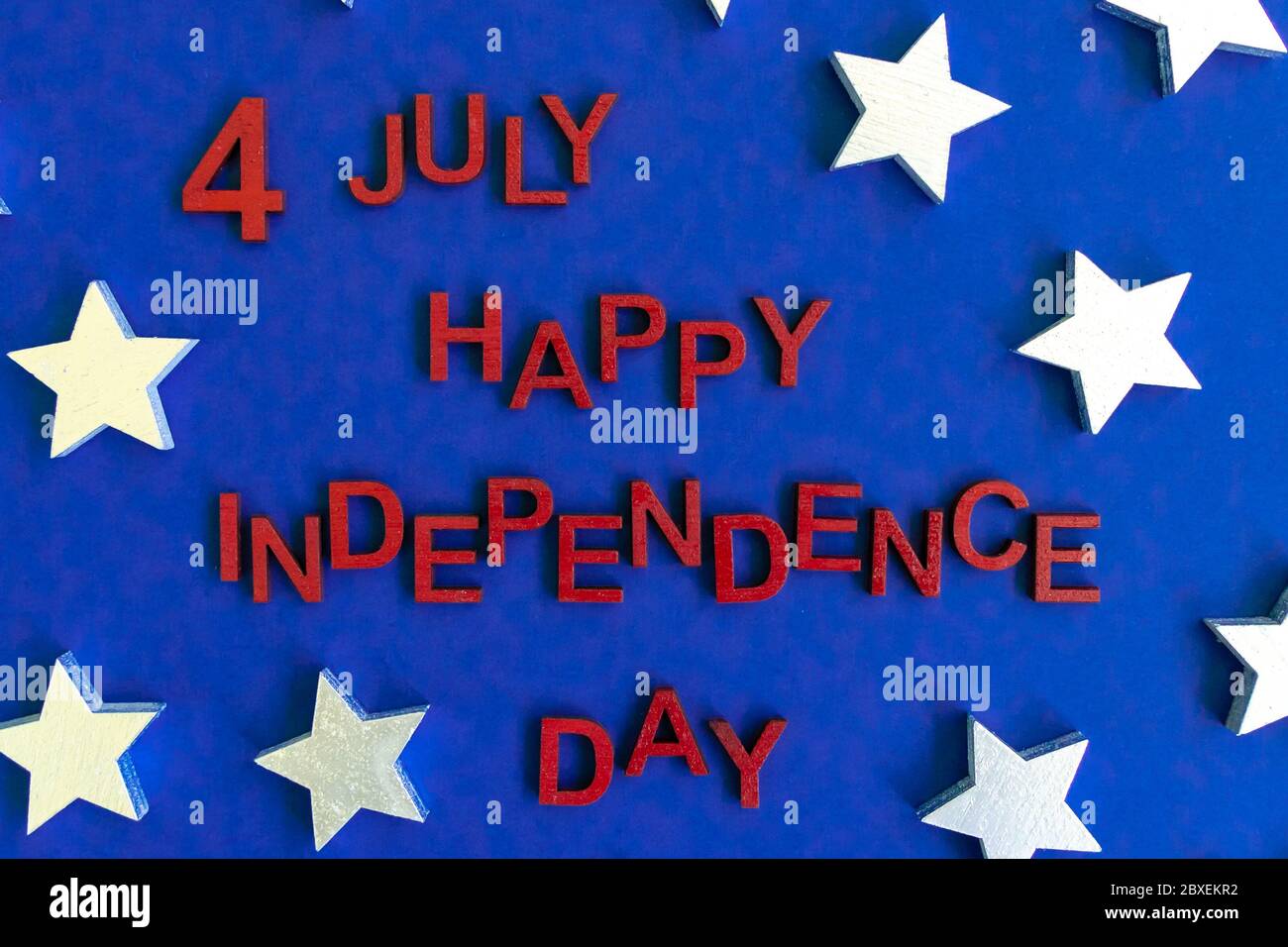 Le parole 4 luglio Happy Independence Day lettere in legno rosso dipinte a mano per un aspetto patriottico. Stelle sullo sfondo. Celebrazione. Biglietto di auguri. Via superiore Foto Stock