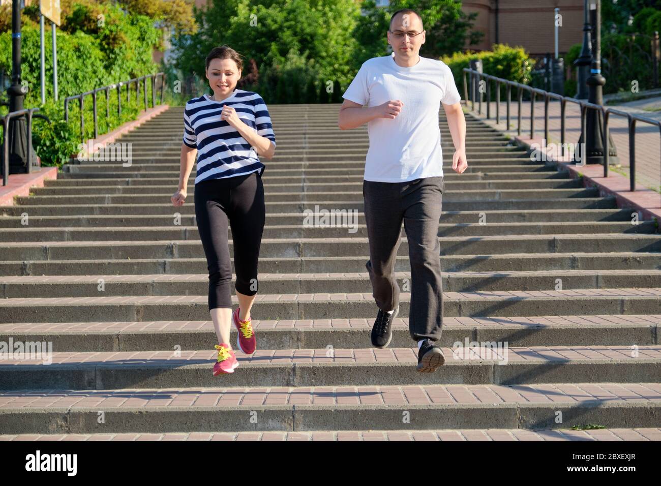 Coppia che corre sulle scale in città, uomo maturo e donna insieme Foto Stock