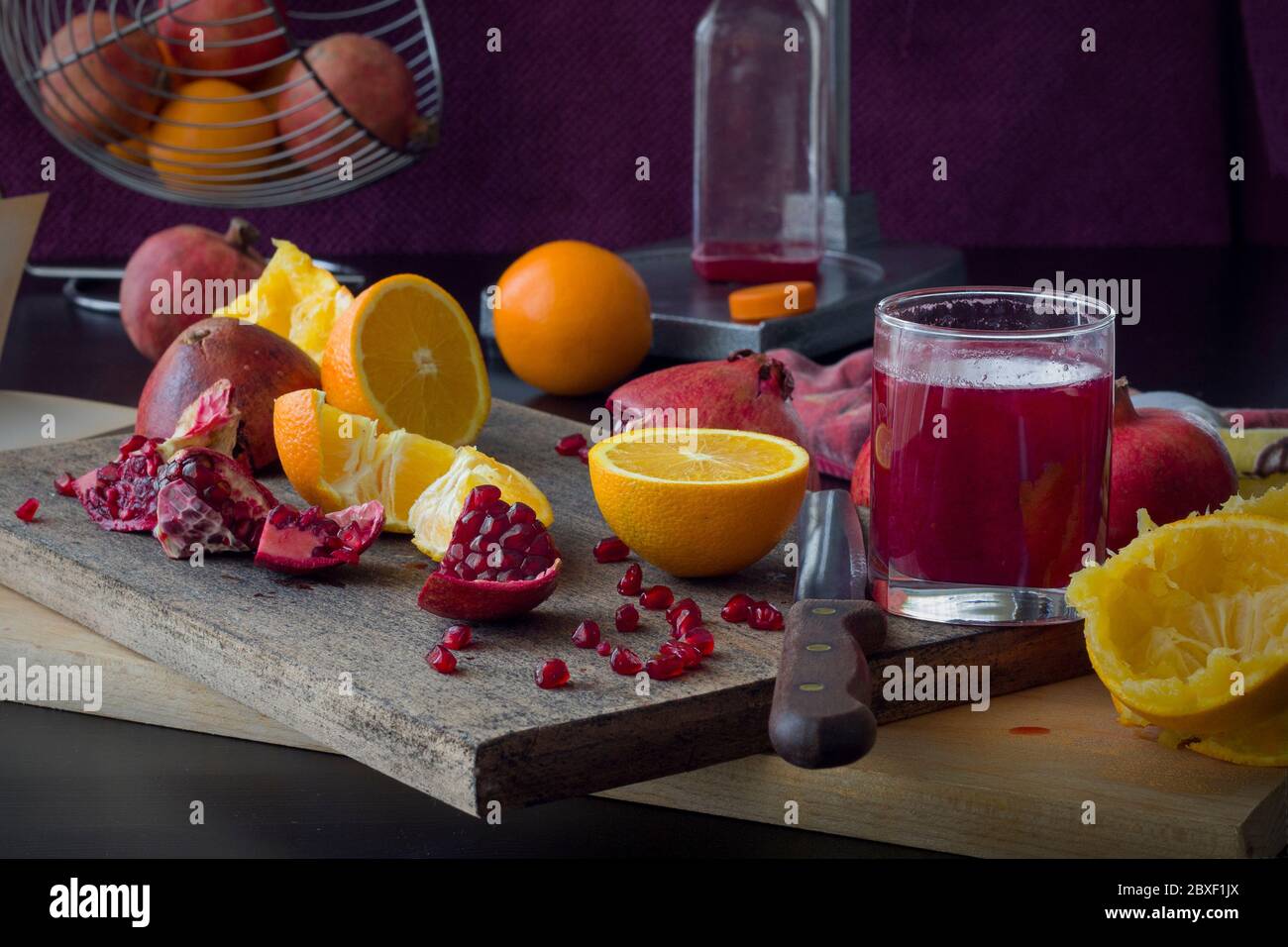 bicchiere di succo di melograno appena spremuto, frutta fresca tagliata a pezzi, il processo di spremitura del succo Foto Stock