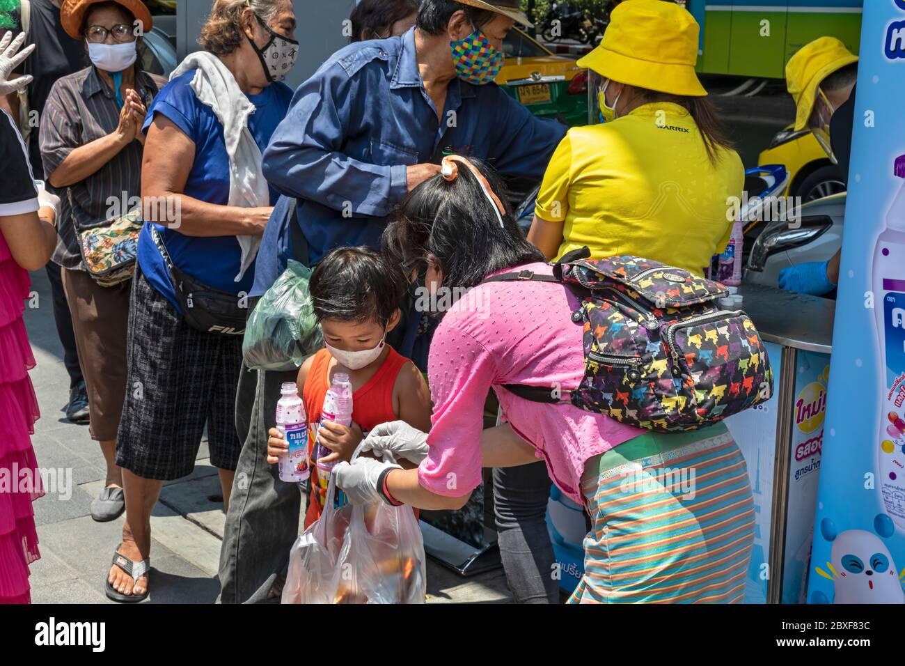 Volontari con maschere e guanti che danno cibo gratuito in cucina di strada durante la pandemia di Covid, Bangkok, Thailandia Foto Stock