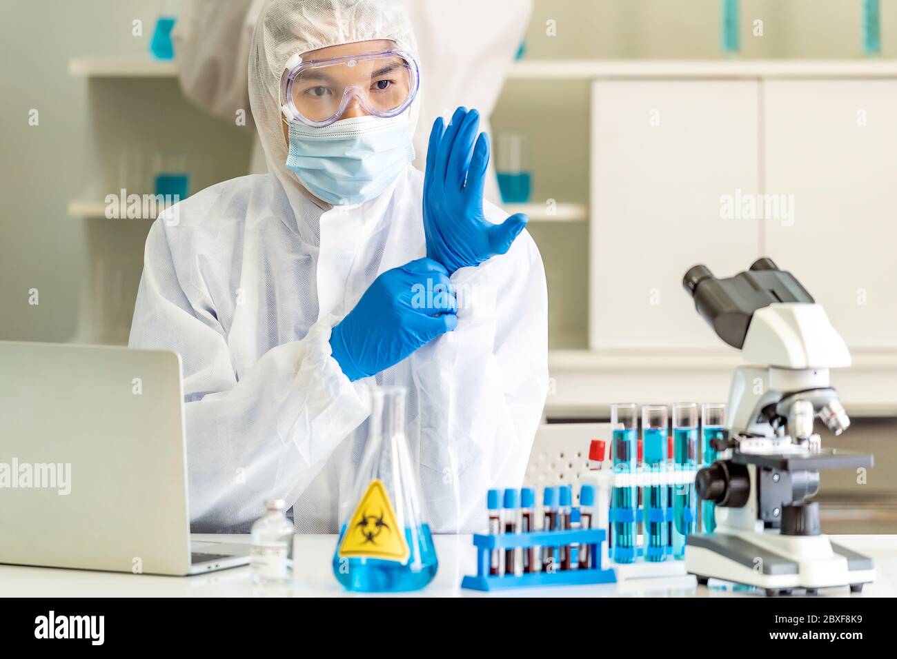 Scienziati asiatici con tuta PPE indossare guanti medici in laboratorio di scienza prima di studiare la ricerca e sperimentare sul vaccino coronavirus covid-19. Medio Foto Stock