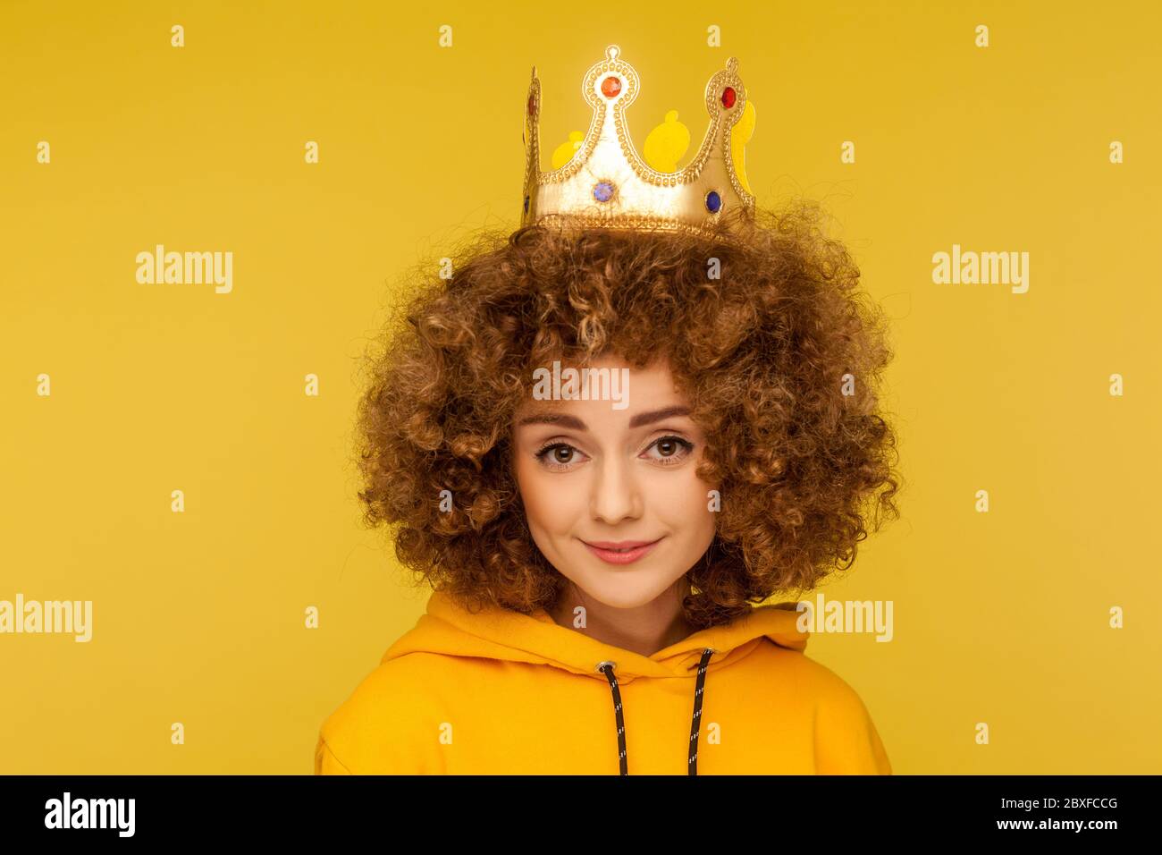 Sono regina! Closeup di bella donna con capelli ricci felice che indossa la corona sulla testa e sorridente, concetto di fiducia in se stessi nel successo, auto-motivazione e d Foto Stock