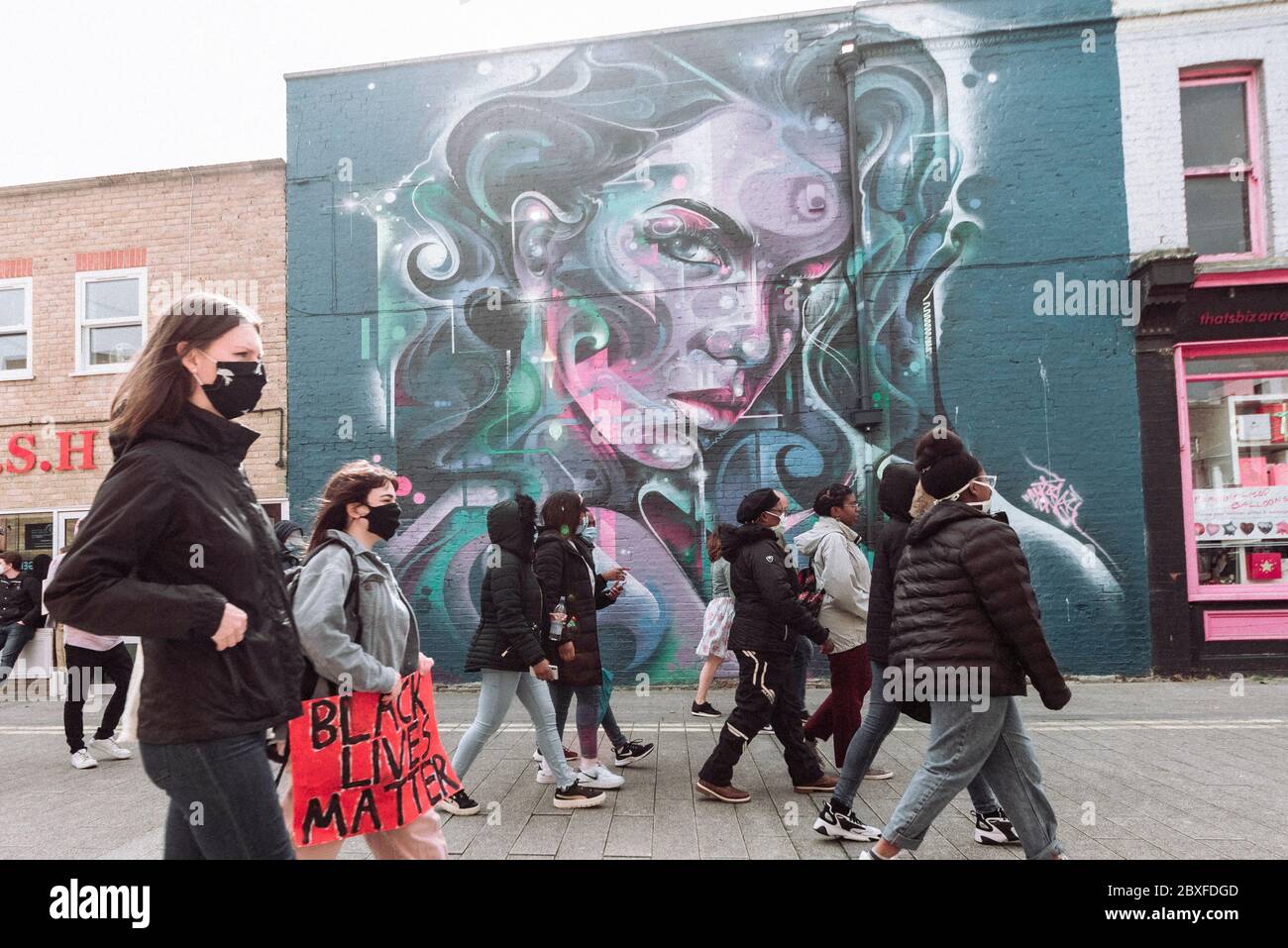 Le persone che lasciano una Black Lives, la questione anti razzismo protesta a Southend on Sea, Essex, Regno Unito, passando grande muro di strada arte murale di donne Foto Stock