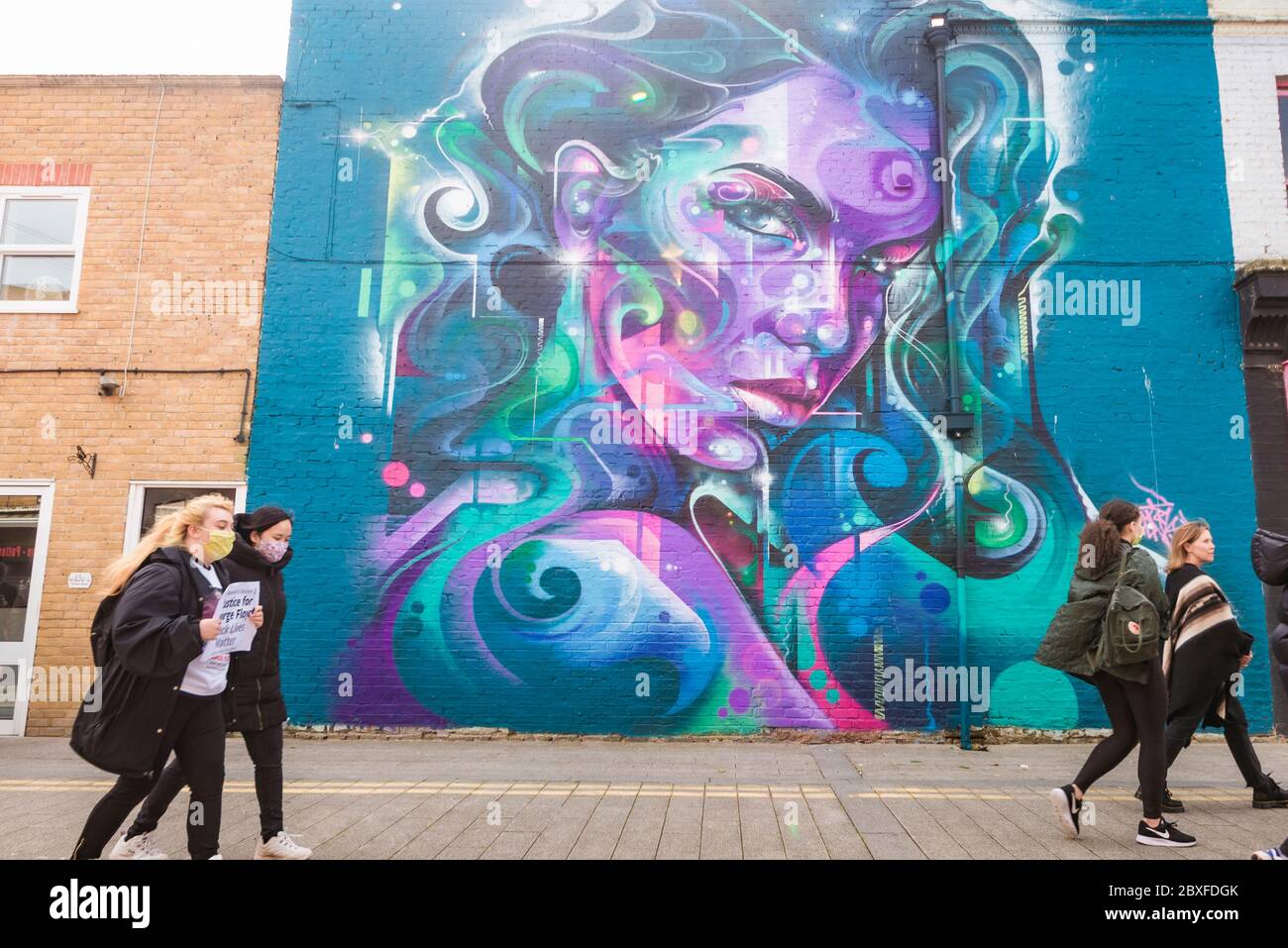 Le persone che lasciano una Black Lives, la questione anti razzismo protesta a Southend on Sea, Essex, Regno Unito, passando grande muro di strada arte murale di donne Foto Stock