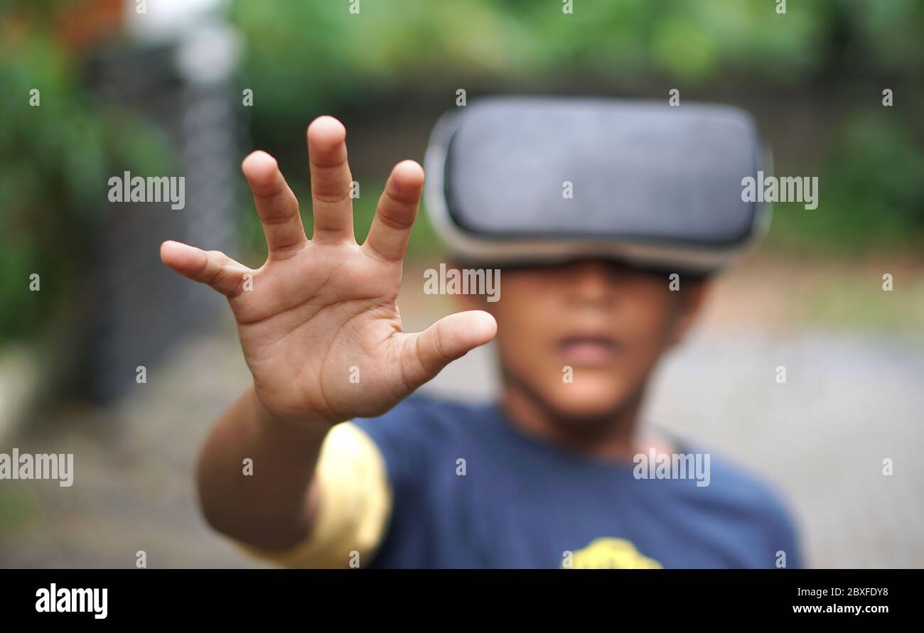 Ragazzo che indossa un dispositivo VR, sorpreso dalla realtà virtuale Foto Stock