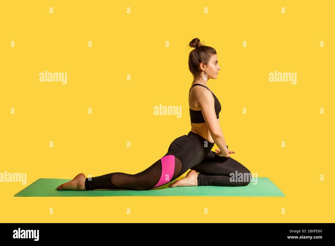 Donna sportiva seria motivata che pratica yoga sul tappetino, facendo una gamba di porcione di piccione, riscaldando i muscoli di allungamento, esercizi di flessibilità. studio Foto Stock
