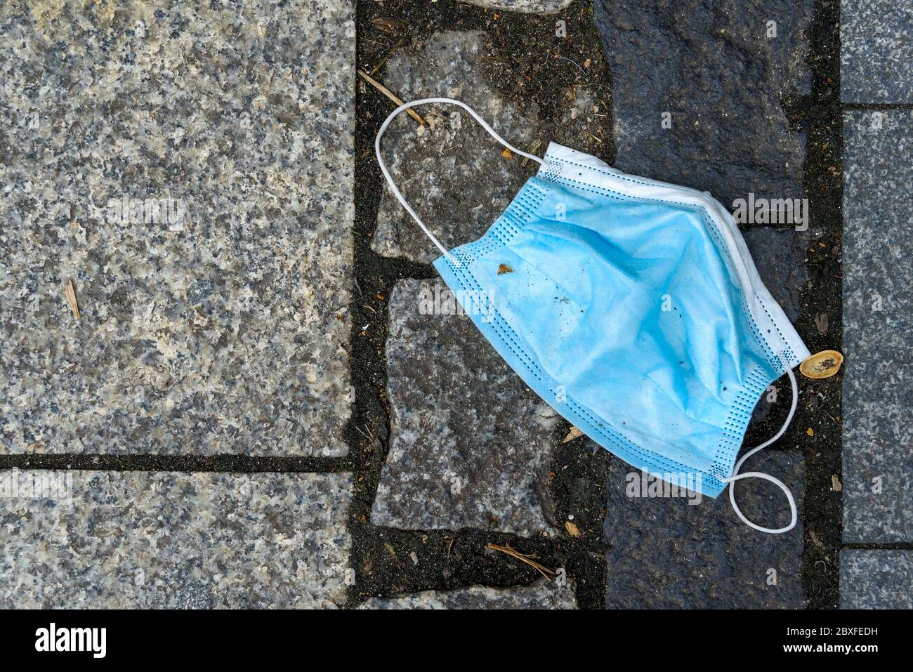 mondo dopo pandemia. Maschera sporca su terra, rifiuti di plastica, inquinamento della natura Foto Stock