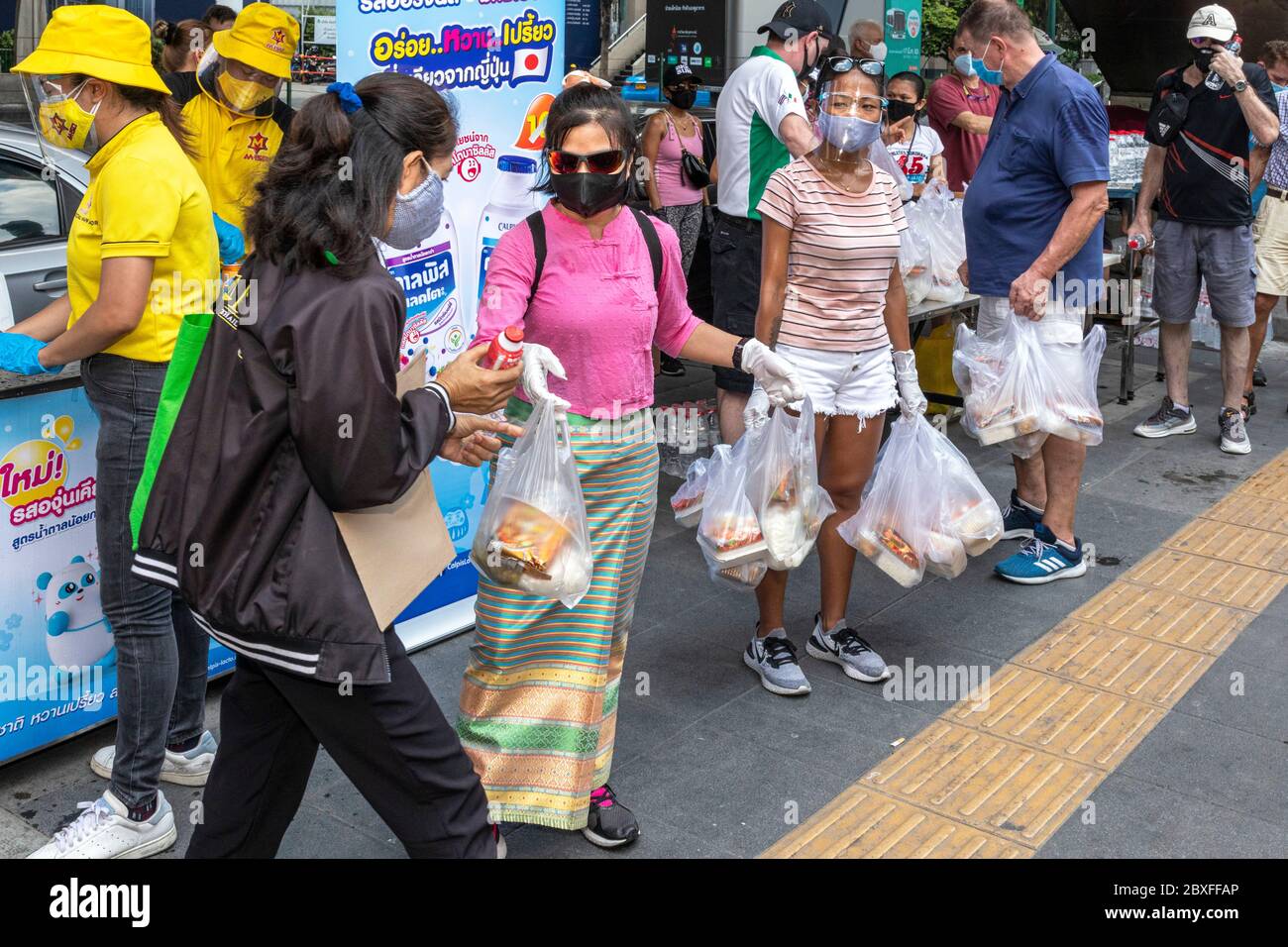 Volontari con maschera facciale e guanti che danno fuori cibo gratuito presso la banca alimentare durante la pandemia di Covid, Bangkok, Thailandia Foto Stock
