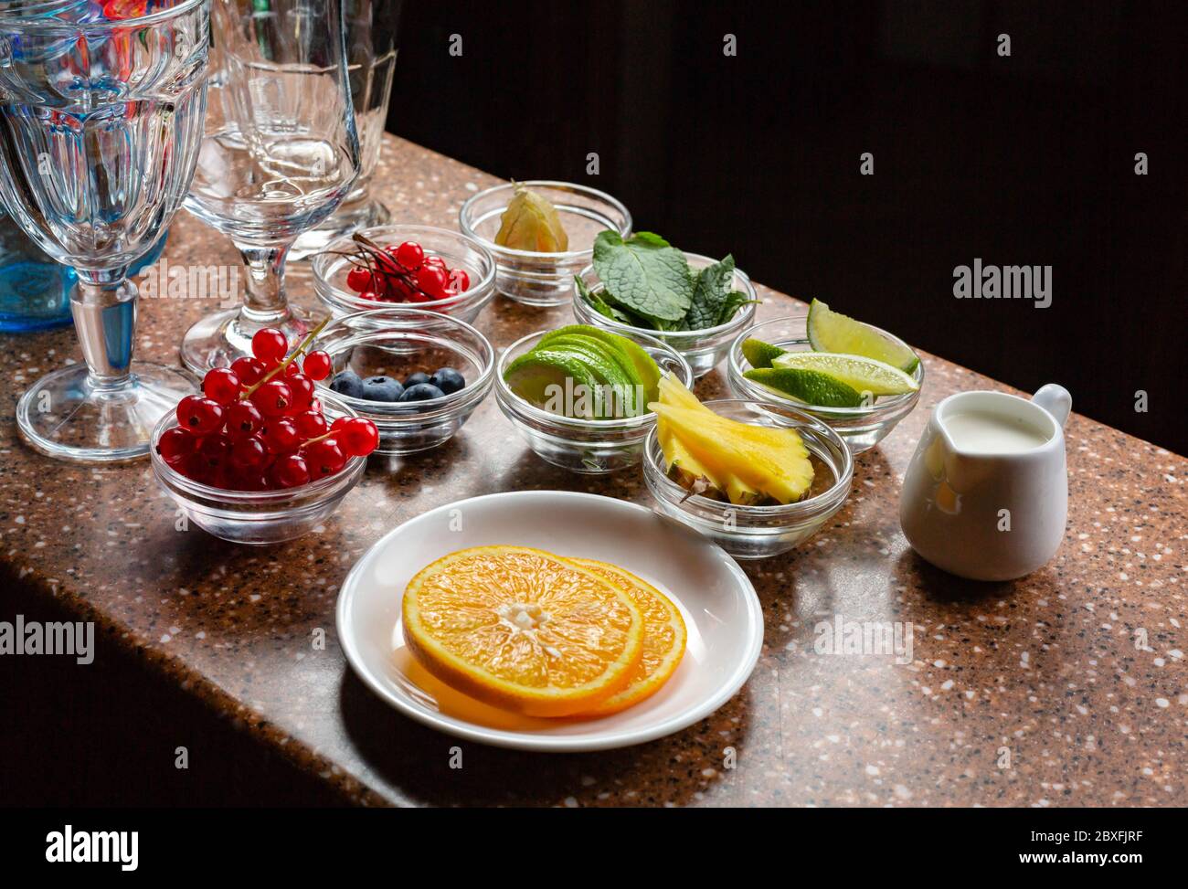 L'ambiente di lavoro del barista. Frutta, bacche e latte sono preparati per la preparazione di cocktail al bar Foto Stock