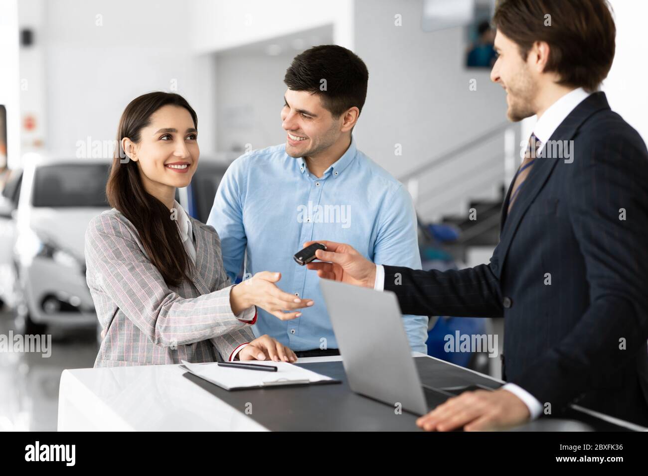 Manager che dà la chiave automatica alla coppia di famiglia Foto Stock