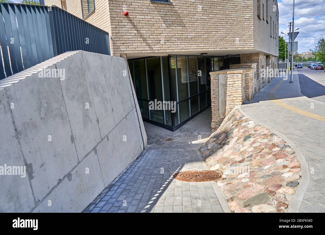 Marciapiede stretto vicino al nuovo edificio e al vecchio muro Foto Stock