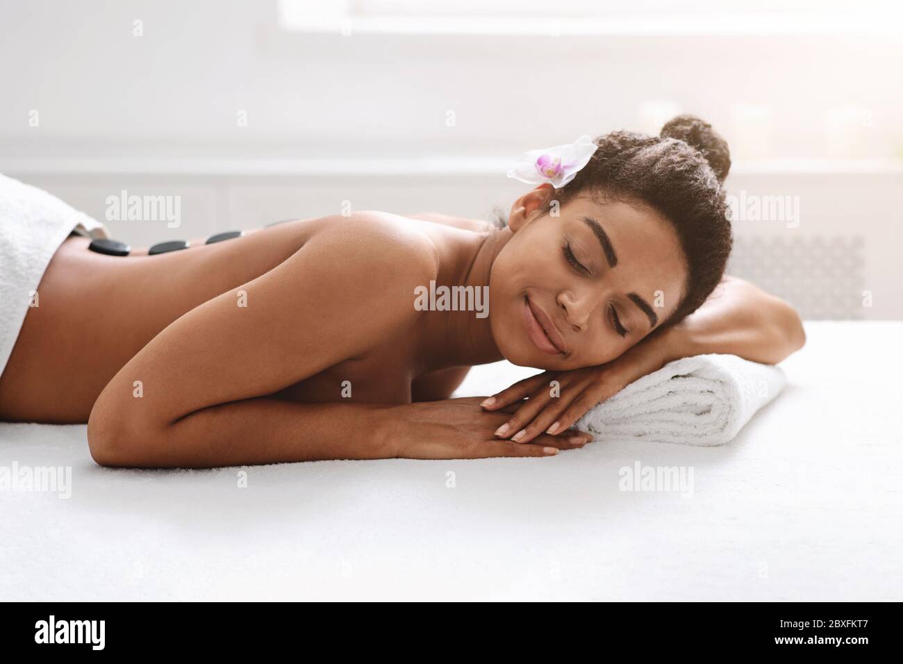 Donna nera riposante durante il massaggio della pietra calda Foto Stock