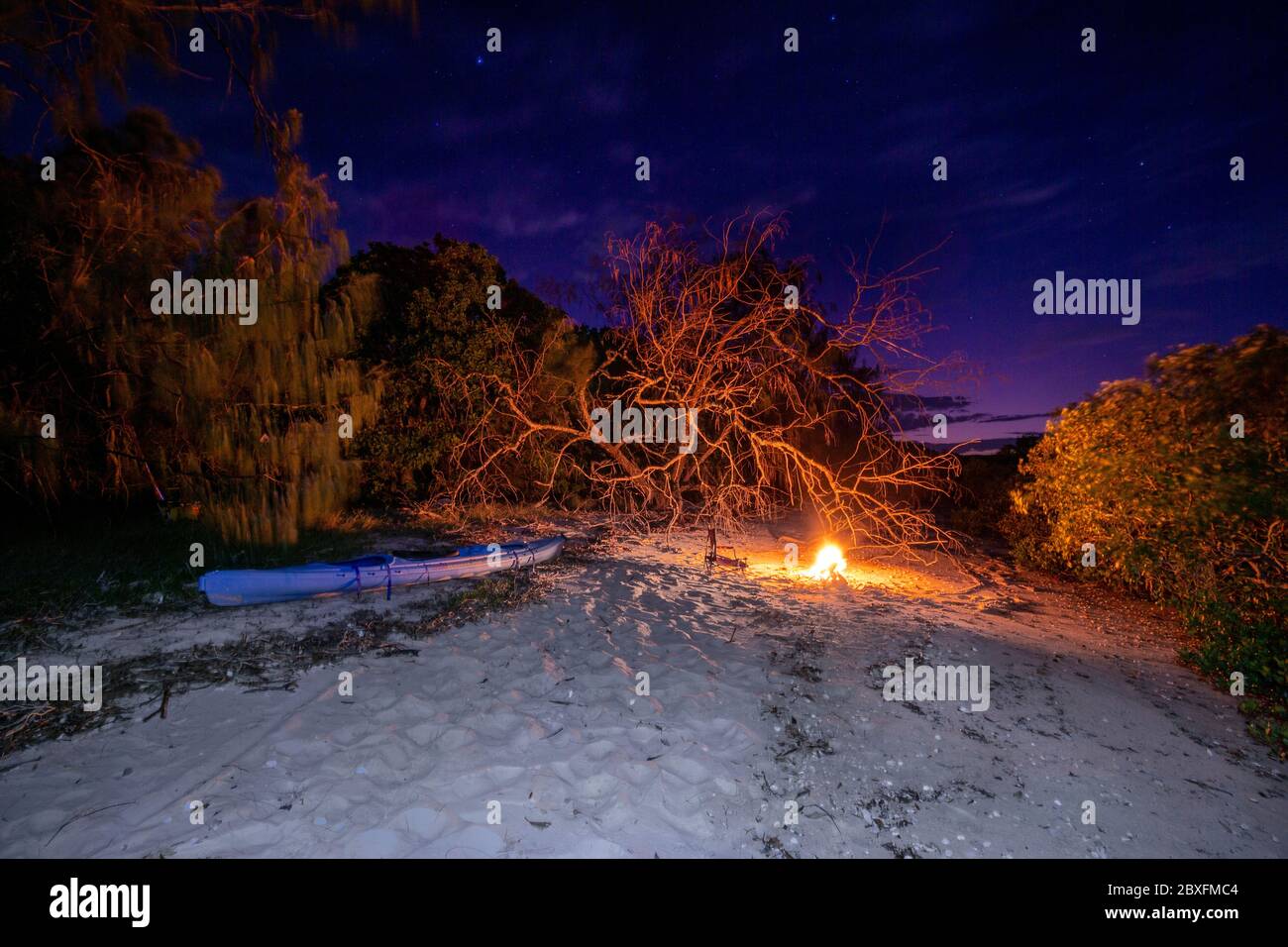 Kayak sdraiato sulla spiaggia sabbiosa vicino al falò di notte Foto Stock