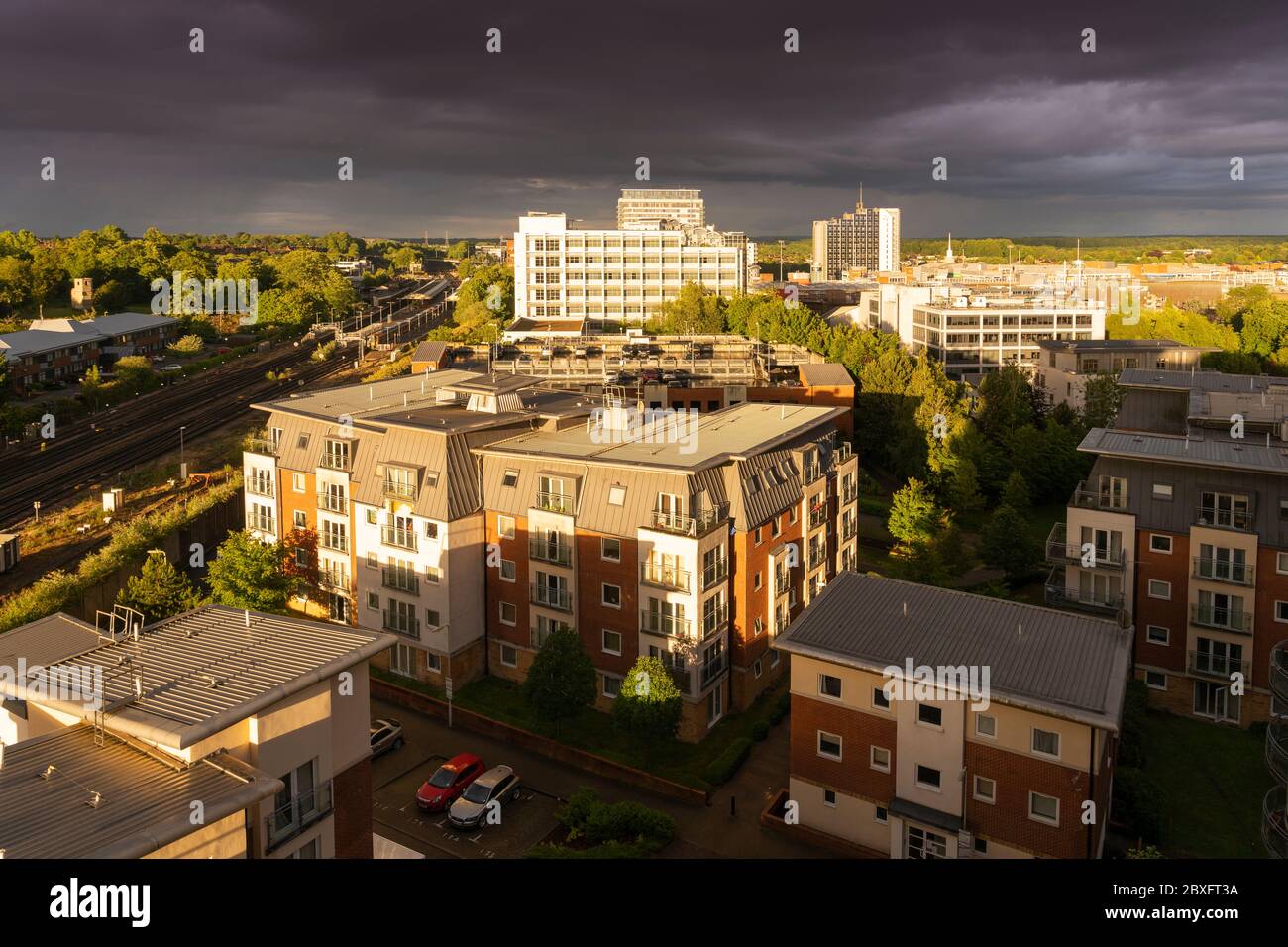 Una vista aerea dall'alto di un cielo tempestoso con le precipuose discese durante il tramonto con una suggestiva illuminazione sul centro di Basingstoke con appartamenti e uffici, Regno Unito Foto Stock