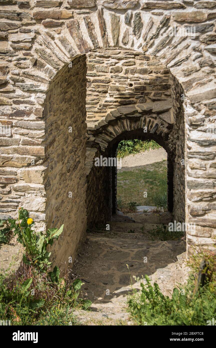 Porta attraverso il muro di un castello medievale rovina. La luce e l'ombra dominano l'immagine. Foto Stock