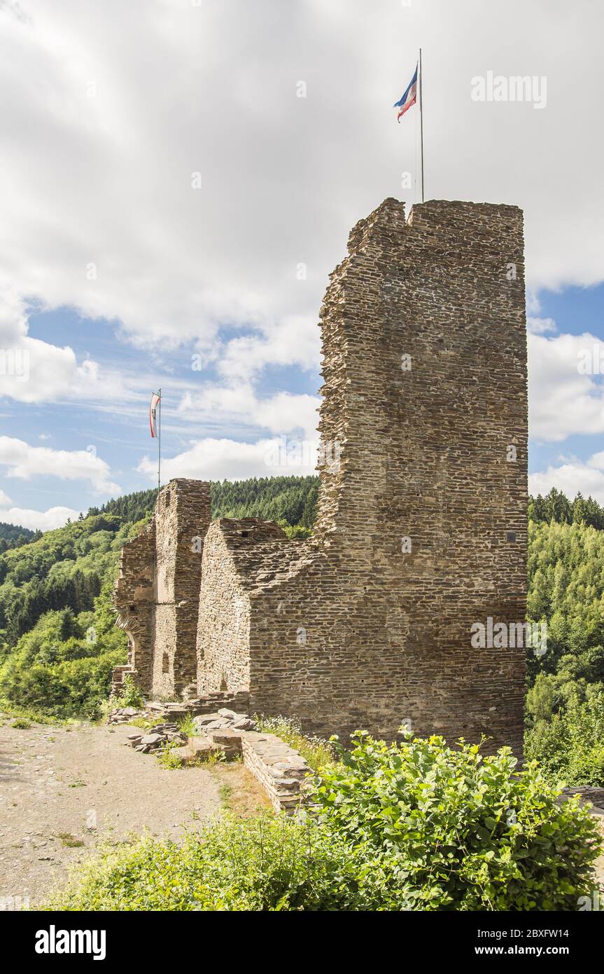 La rovina della torre di un castello medievale, illuminato dal sole in una giornata estiva leggermente nuvolosa. Bandiere in alto. Foto Stock