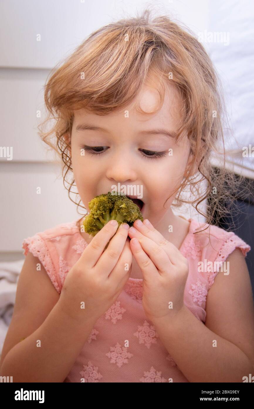 Ritratto di una ragazza che mangia broccoli Foto Stock