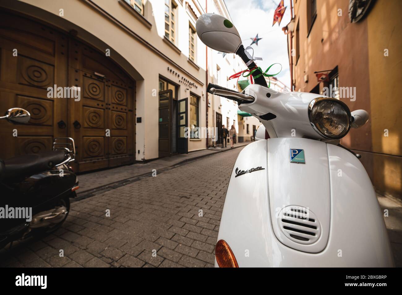 Uno scooter bianco in Vespa parcheggiato nella Città Vecchia di Vilnius, Lituania Foto Stock