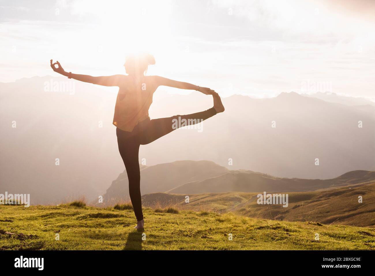 Donna in piedi in montagna facendo yoga, Aubisque, Pirenei, Francia Foto Stock