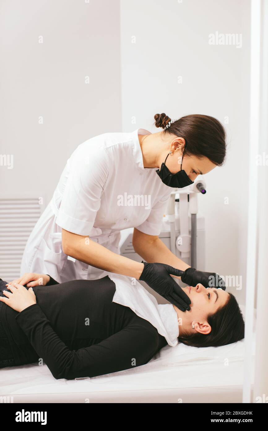 Estetista preparando una donna per un trattamento di bellezza con buccia di carbonio in una clinica Foto Stock