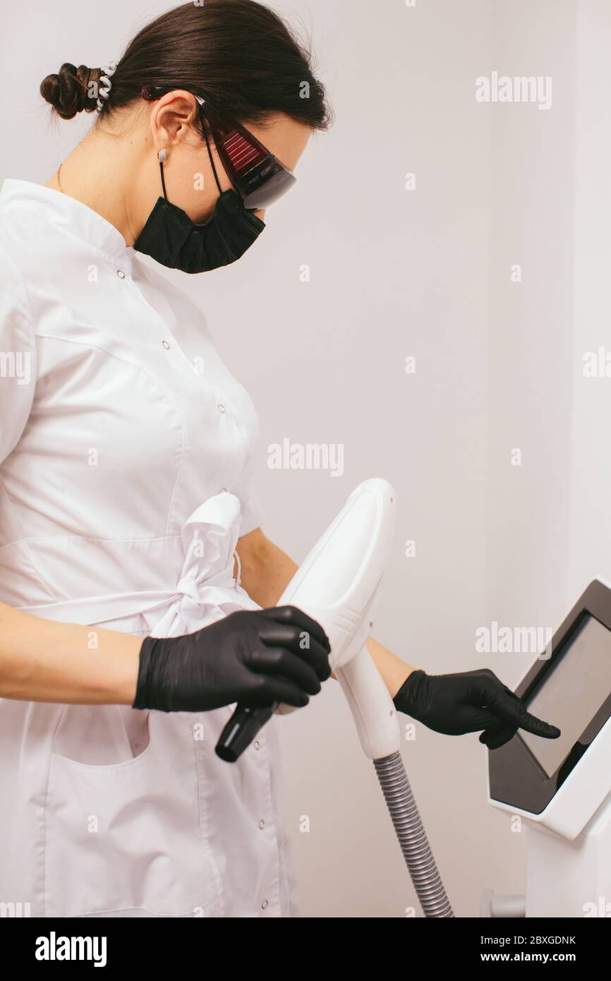 Estetista in una clinica di bellezza in piedi da una macchina di peeling del carbonio Foto Stock