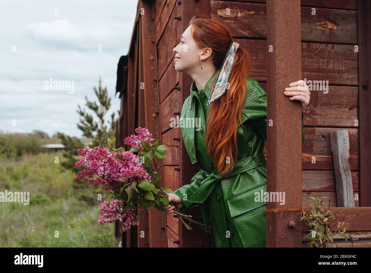 Ritratto di una donna in piedi su un portico che tiene un mazzo di fiori Foto Stock