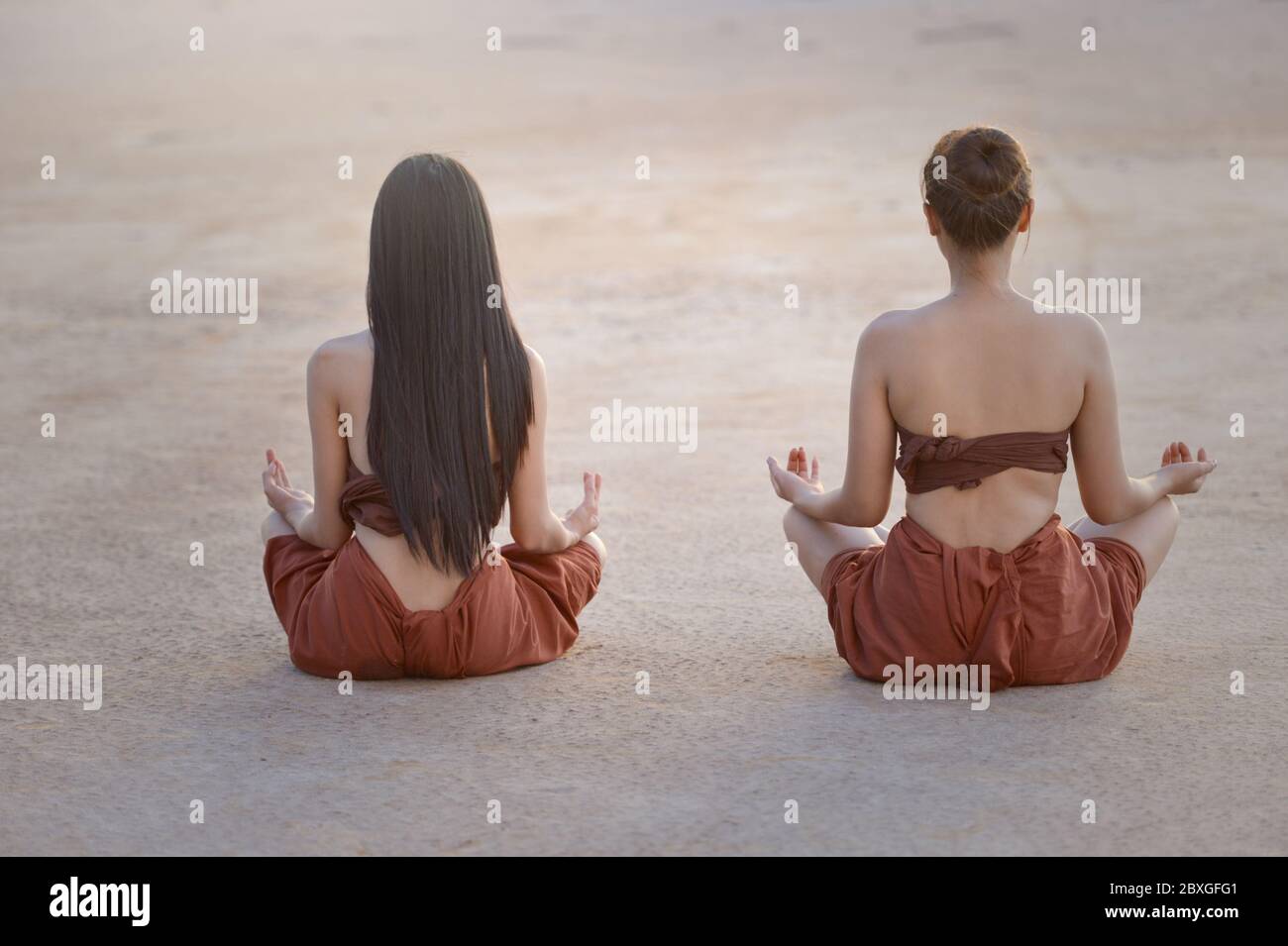 Vista posteriore di due donne che praticano yoga all'aperto, Thailandia Foto Stock