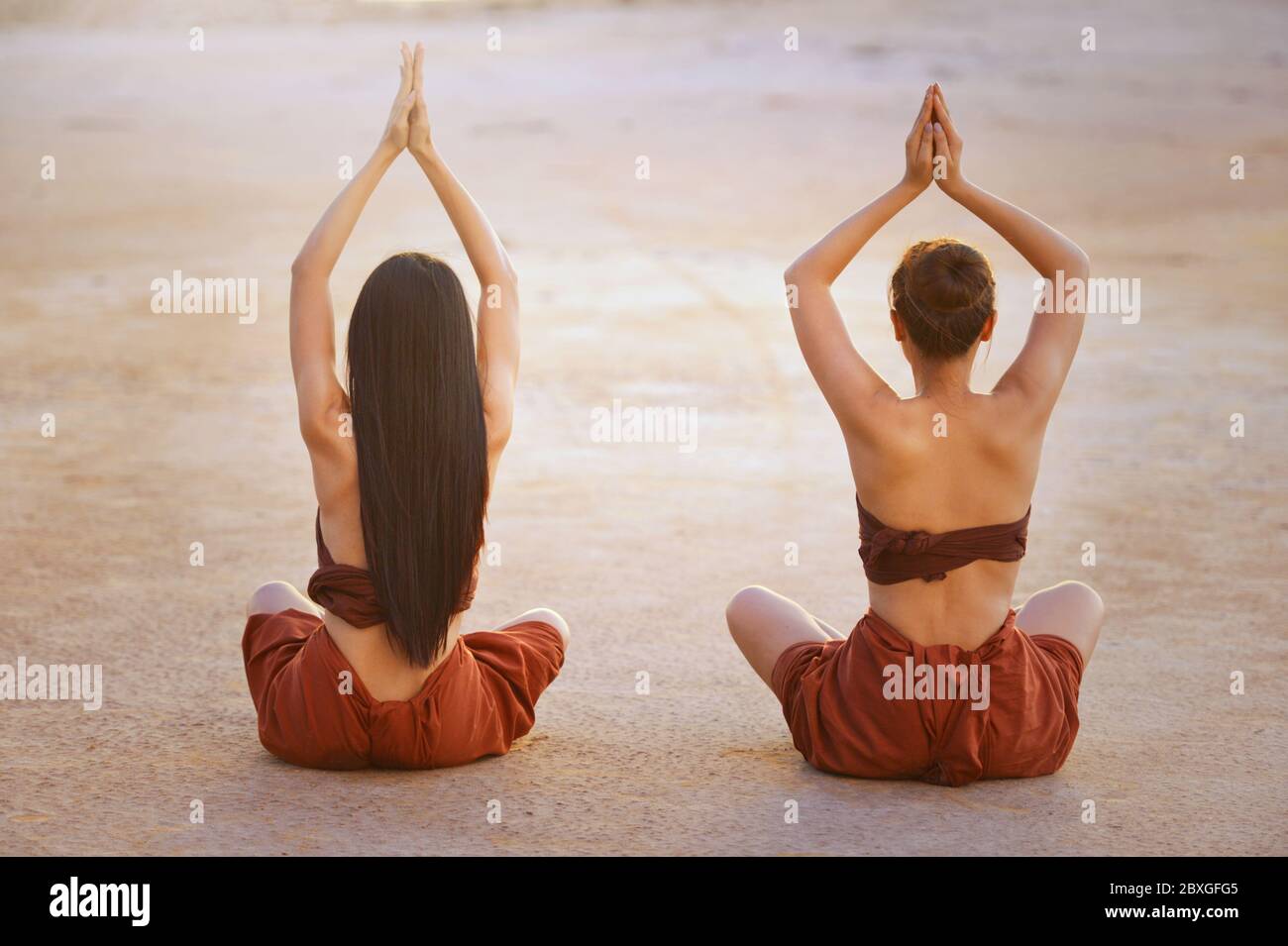 Vista posteriore di due donne che praticano yoga all'aperto, Thailandia Foto Stock