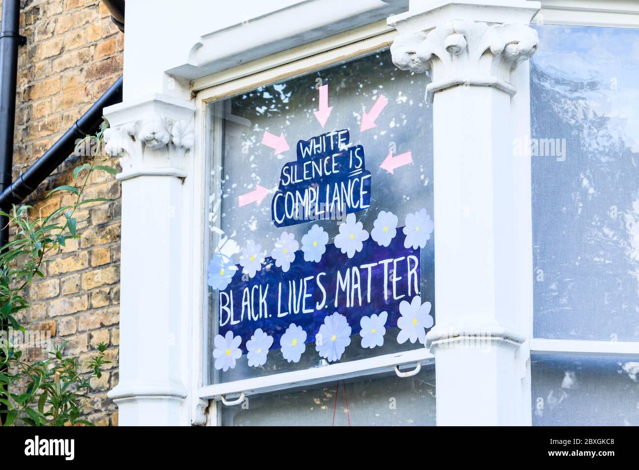 Un poster che legge 'il silenzio bianco è conformità' a sostegno della Black Lives materia nella finestra anteriore di un immobile residenziale a Londra del Nord, Regno Unito Foto Stock