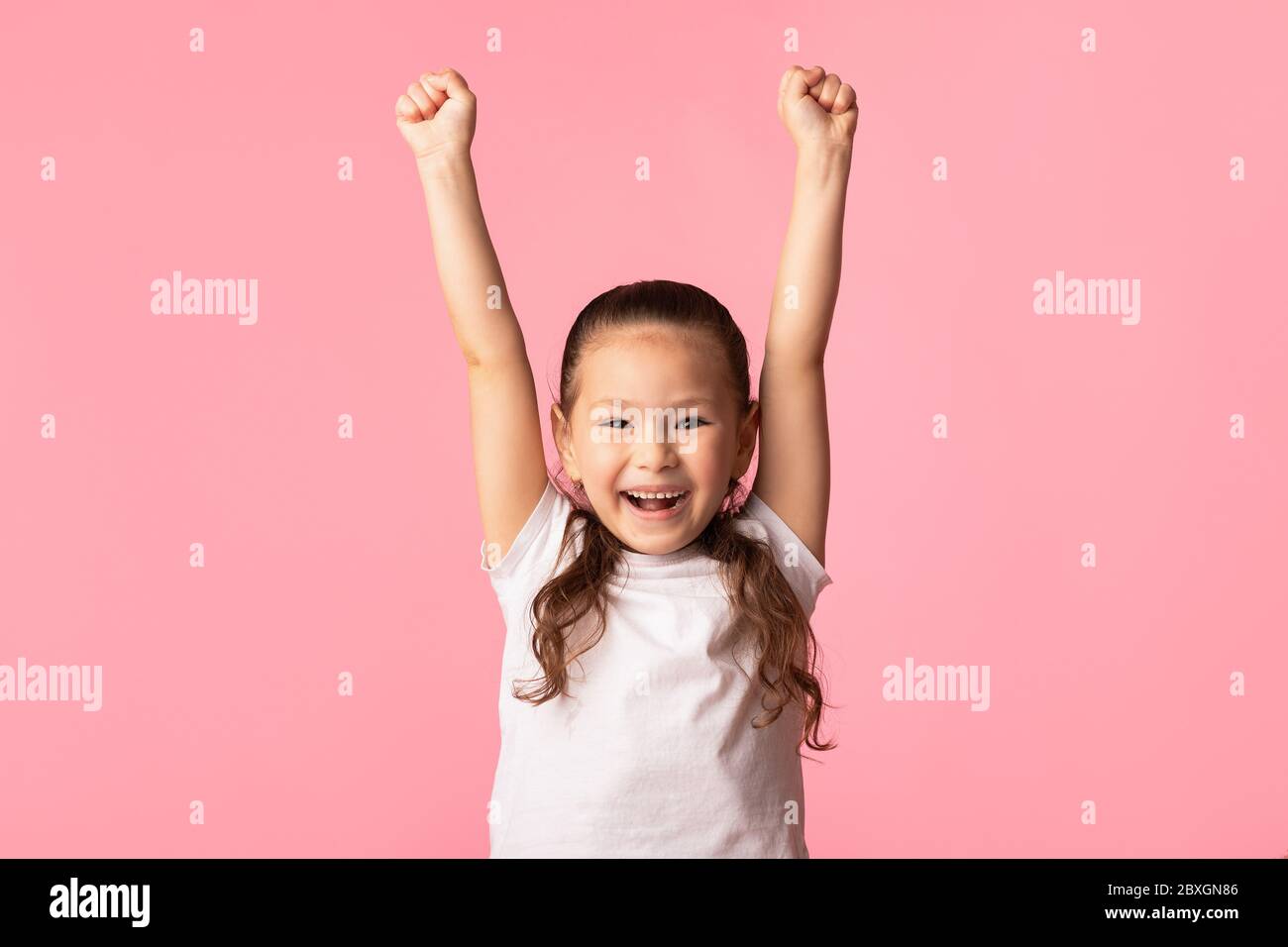 Felice ragazza asiatica che solleva pugni, facendo gesto vincitore Foto Stock