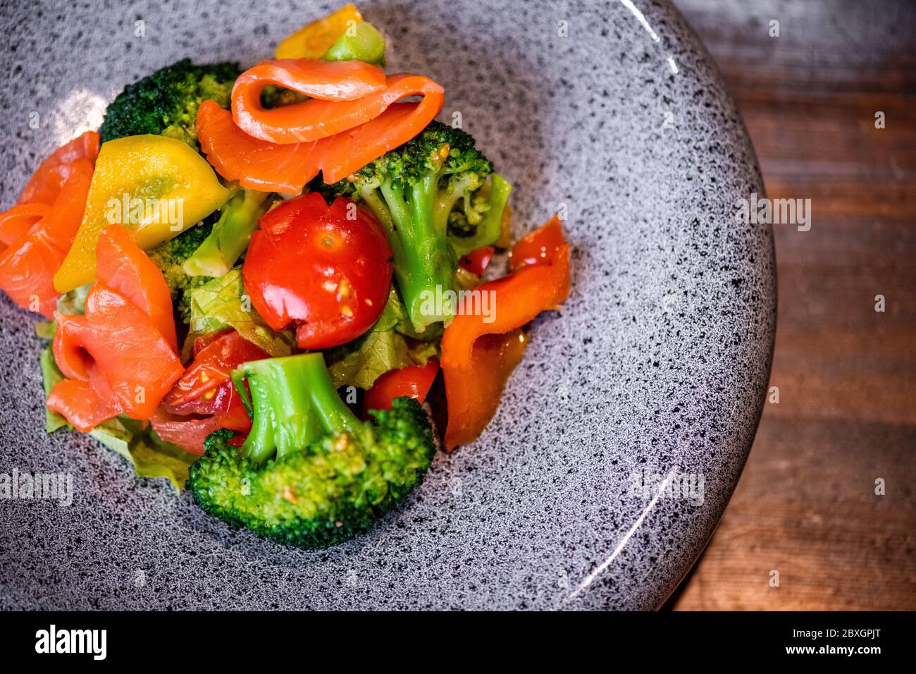Vista sopra insalata estiva con fette di salmone su piatto con struttura in pietra Foto Stock