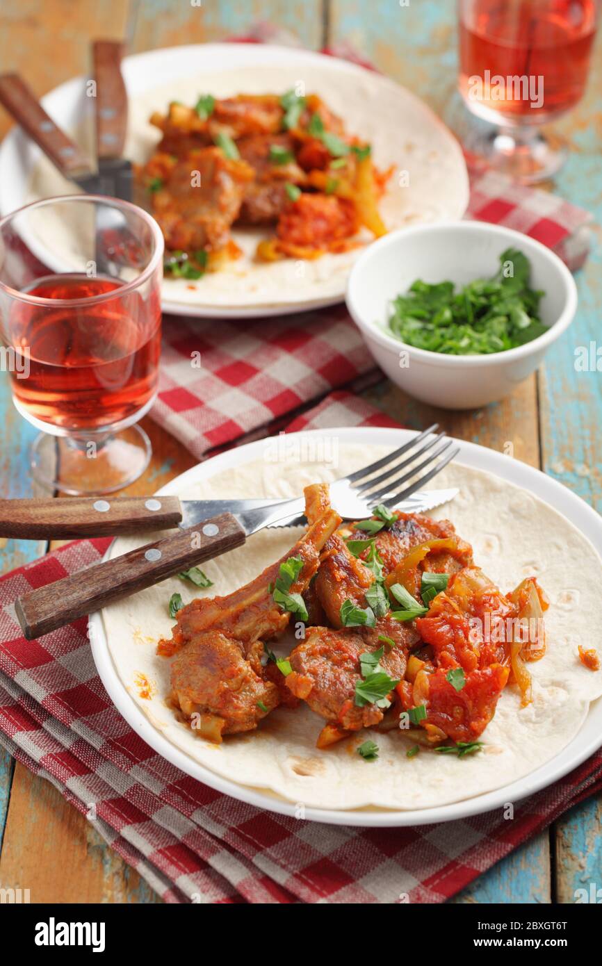 Arrosto di costolette di agnello con pomodoro e pepe su un tavolo rustico Foto Stock