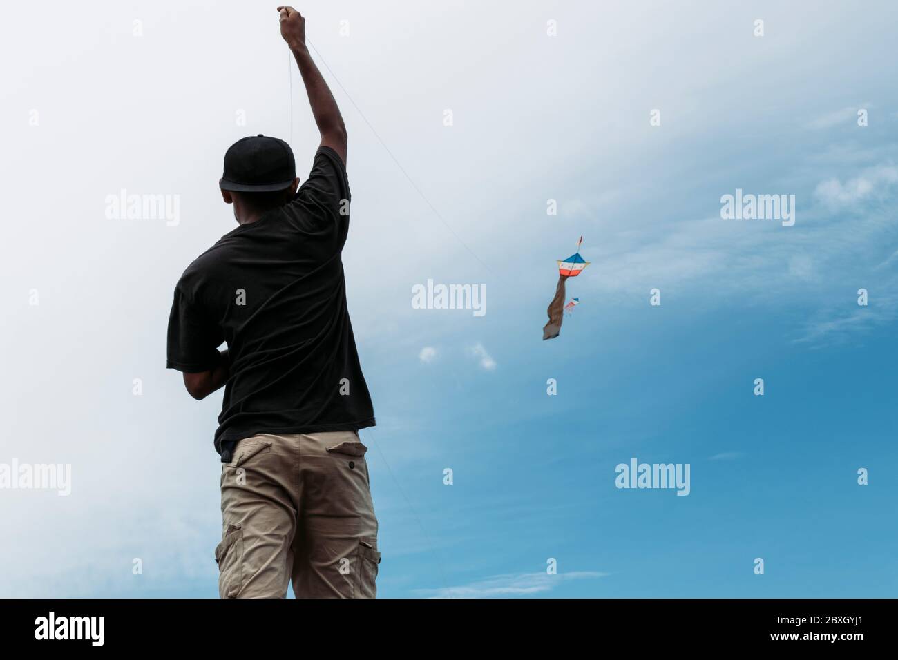 Fotografia di un ragazzo che vola un aquilone su una riva del fiume Foto Stock