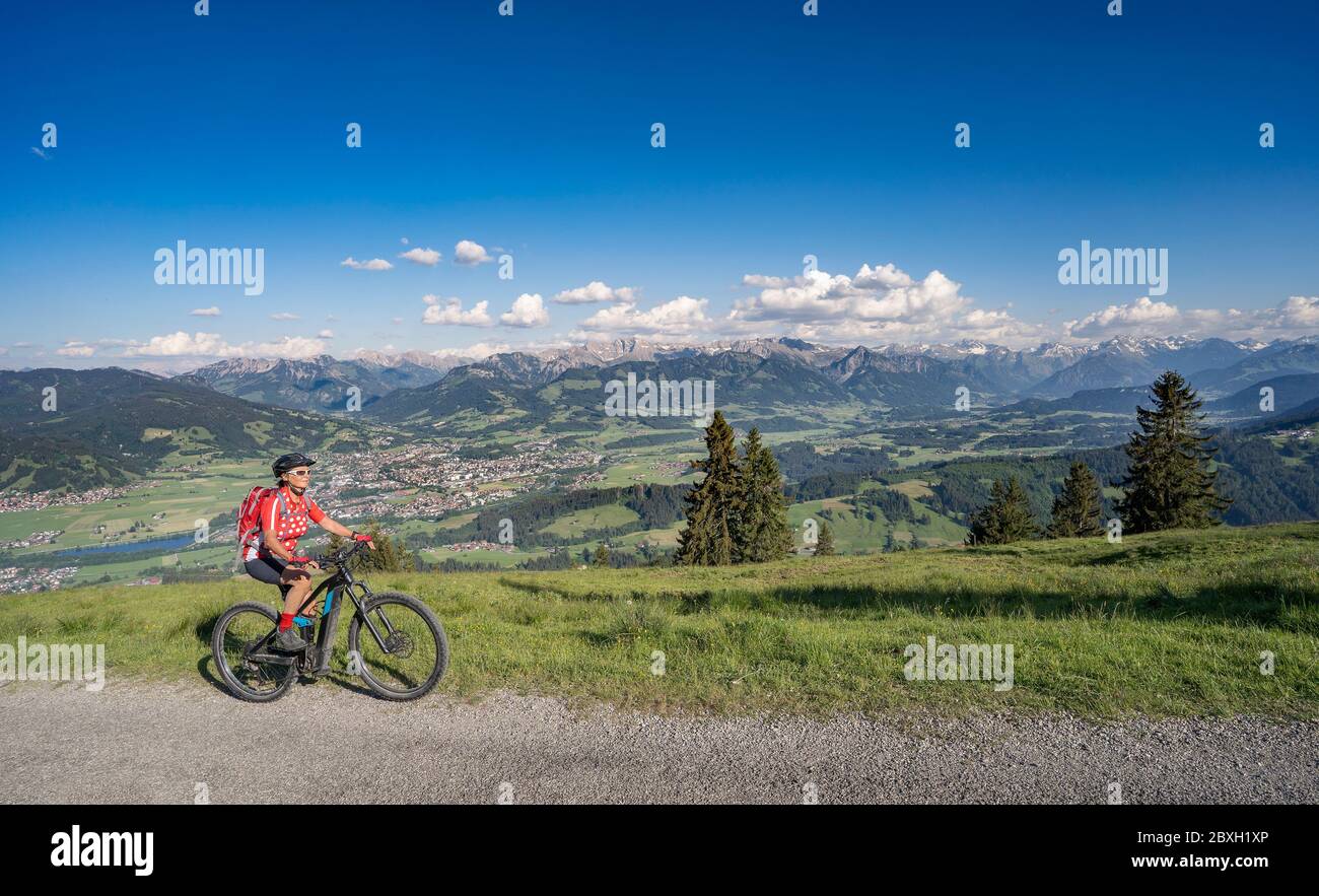 Donna anziana che cavalca la sua mountain bike elettrica sulle montagne sopra la valle dell'Iller tra Sonthofen e Oberstdorf, Alpi Allgau, Baviera G. Foto Stock