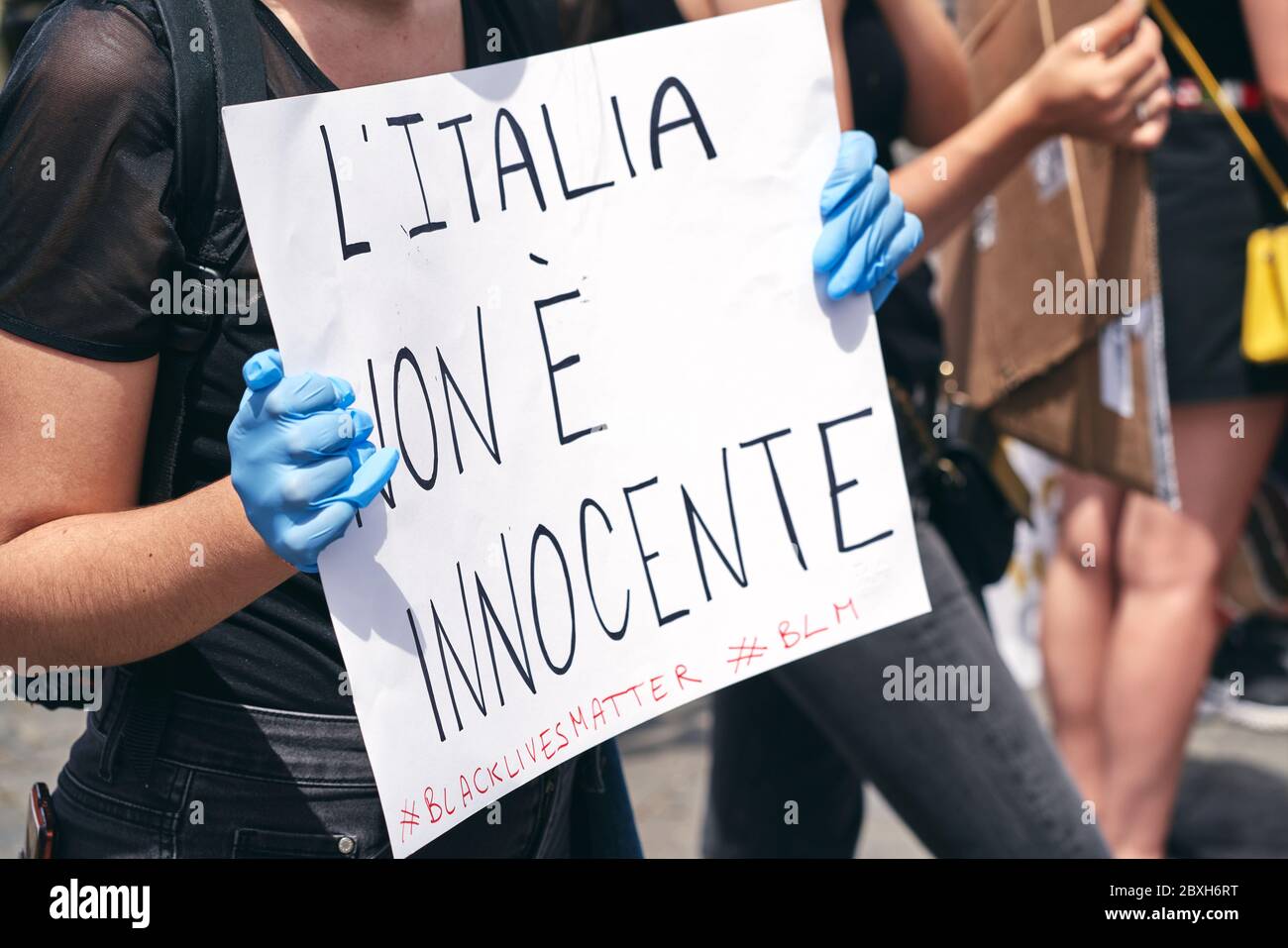 Black Lives Matter, protesta in memoria di George Floyd contro il razzismo. Hands in Blue Guanti tenere un segno in Italiano, lettura: L'Italia non è innocente Foto Stock