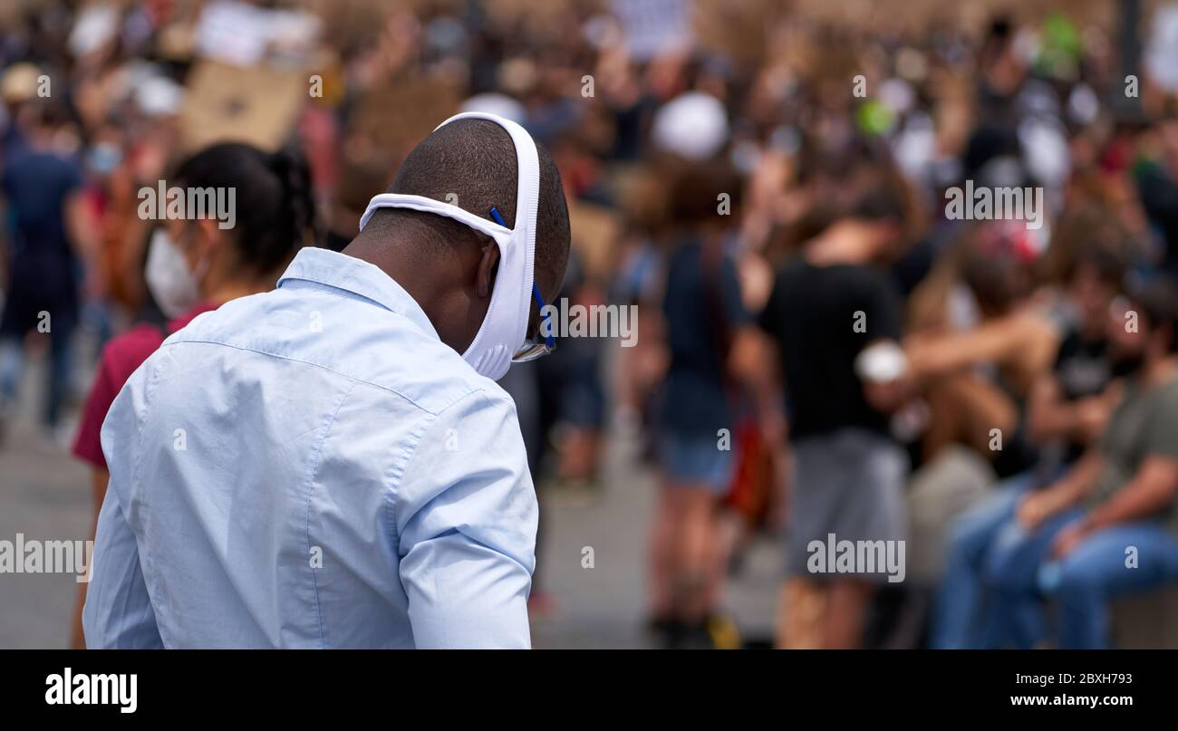 Black Lives Matter, dimostrazione in memoria di George Floyd contro il razzismo. Un uomo nero con una maschera facciale bianca e spessa guarda in basso mentre lutto Foto Stock