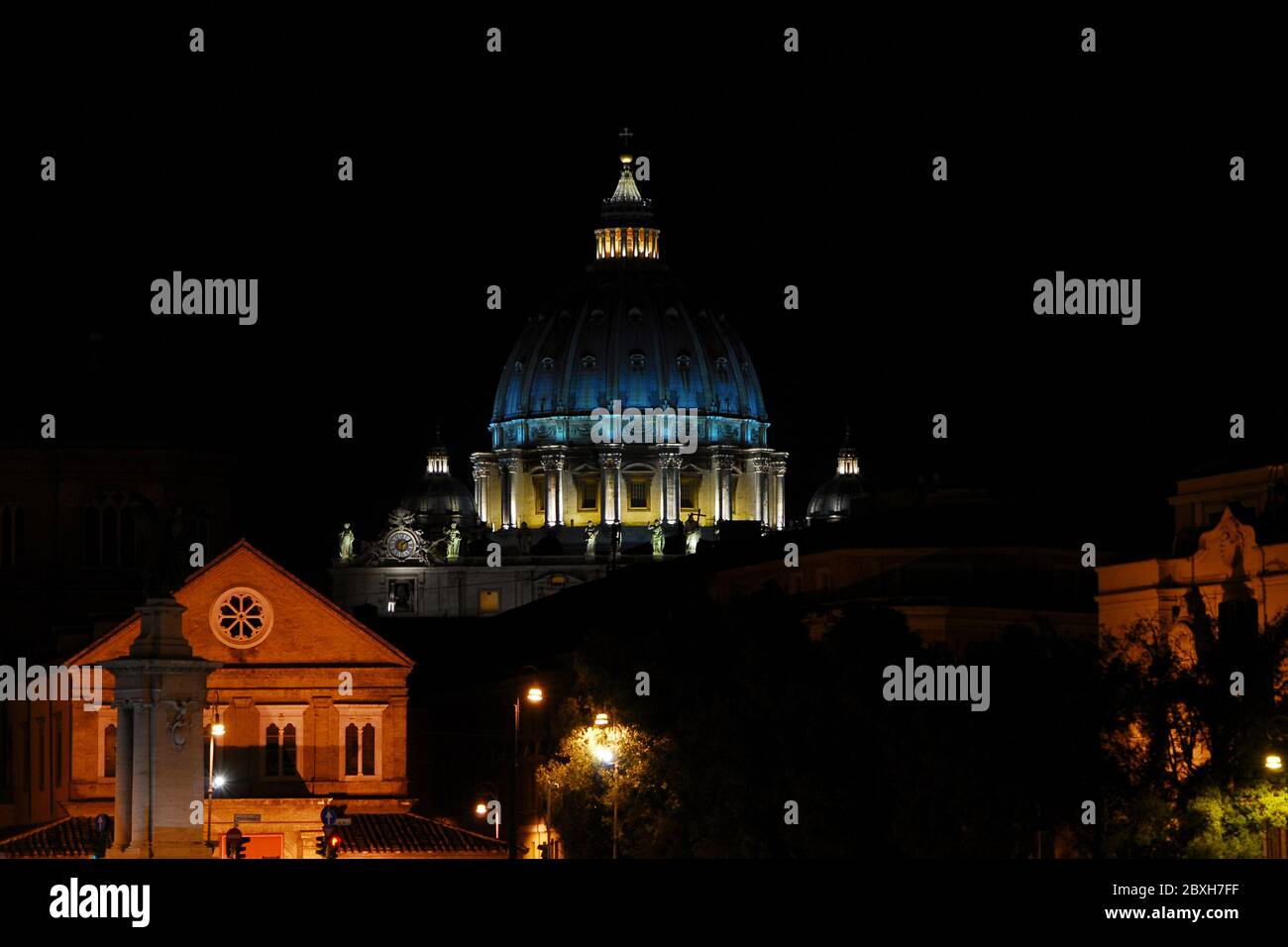 Notte a Roma. Vista dell'iconica cupola di San Pietro illuminata, nel centro storico della città Foto Stock