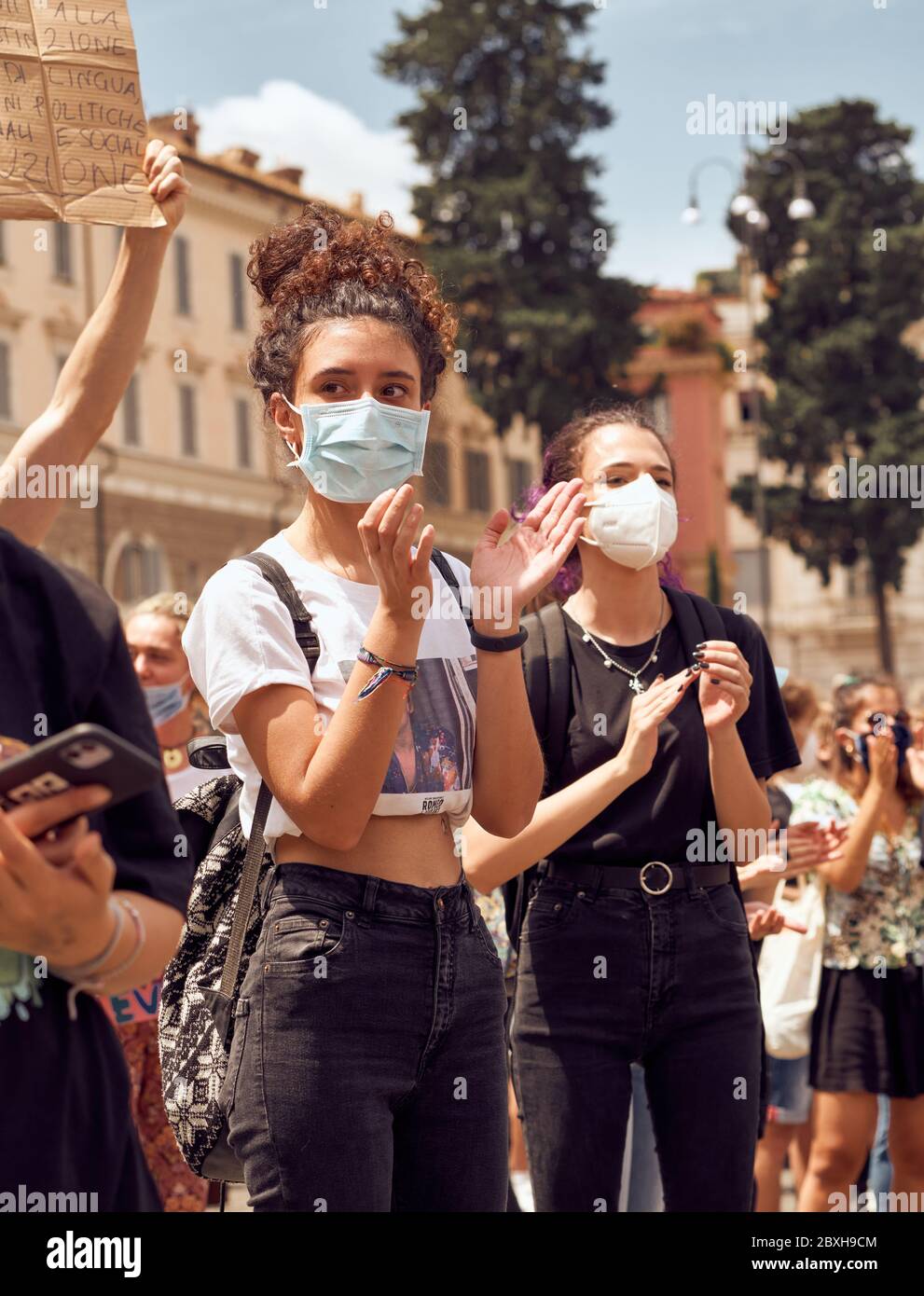 Black Lives Matter, dimostrazione in memoria di George Floyd contro il razzismo. Due ragazze che si aggrappano, indossando maschere per il viso a causa di Coronavirus Pandemic Foto Stock
