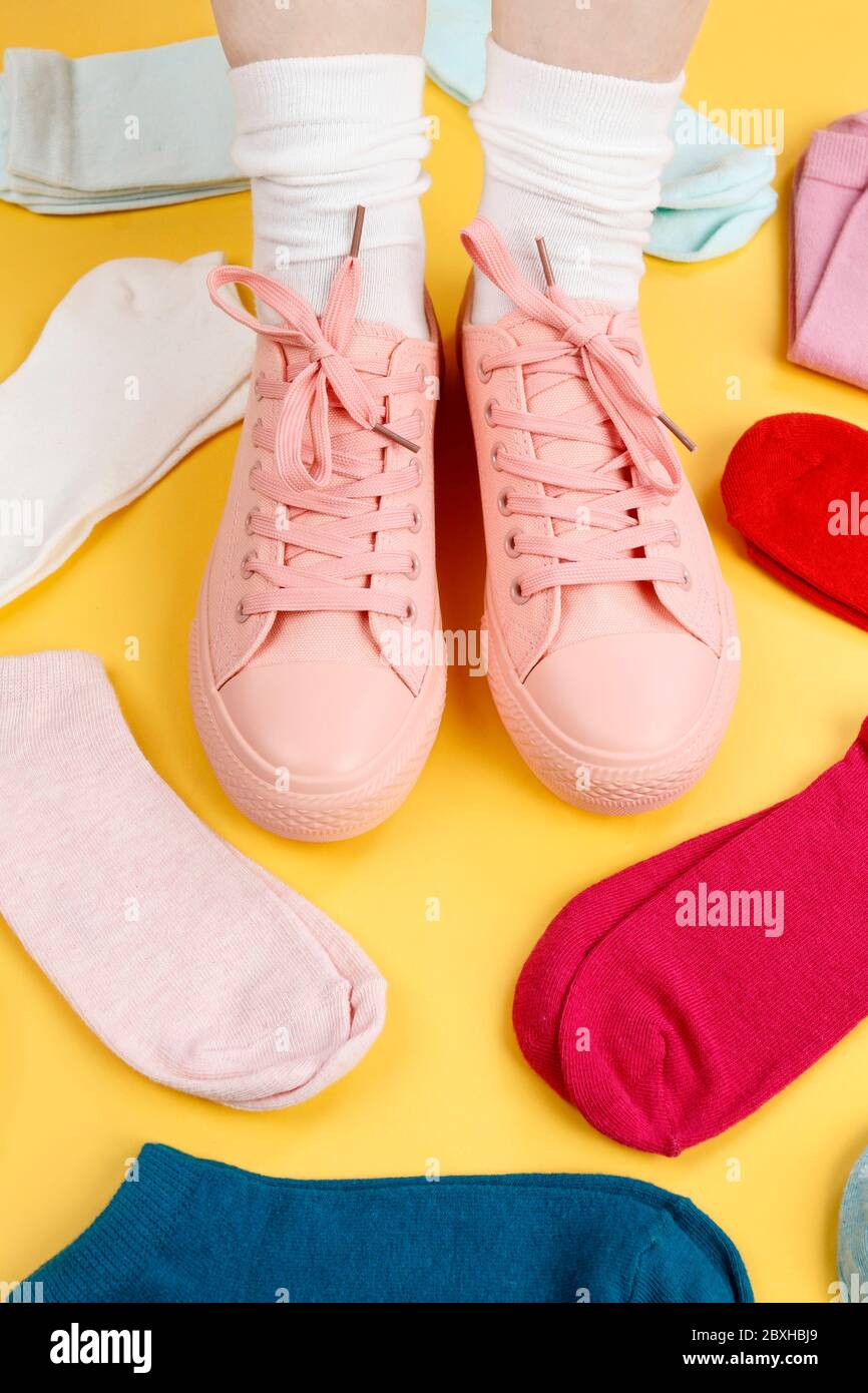 Piedi femminili in sneakers rosa e molti calzini in diversi colori. Tempo di vestiario Foto Stock