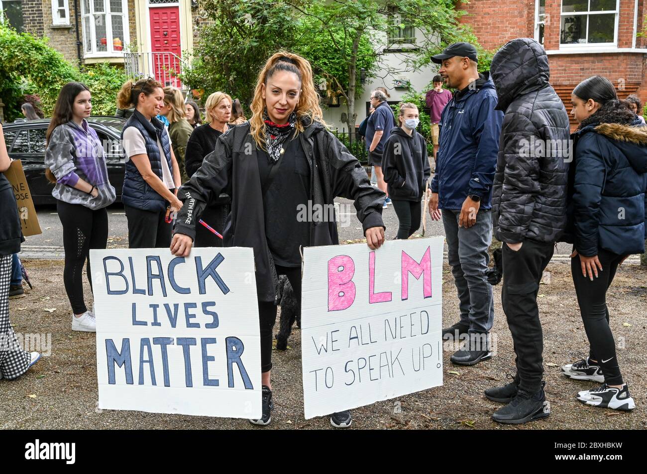 Donna mista con due cartelli "Black Lives Matter", "BLM abbiamo tutti bisogno di parlare in su" circondato da famiglia e amici in una dimostrazione. Londra. Foto Stock
