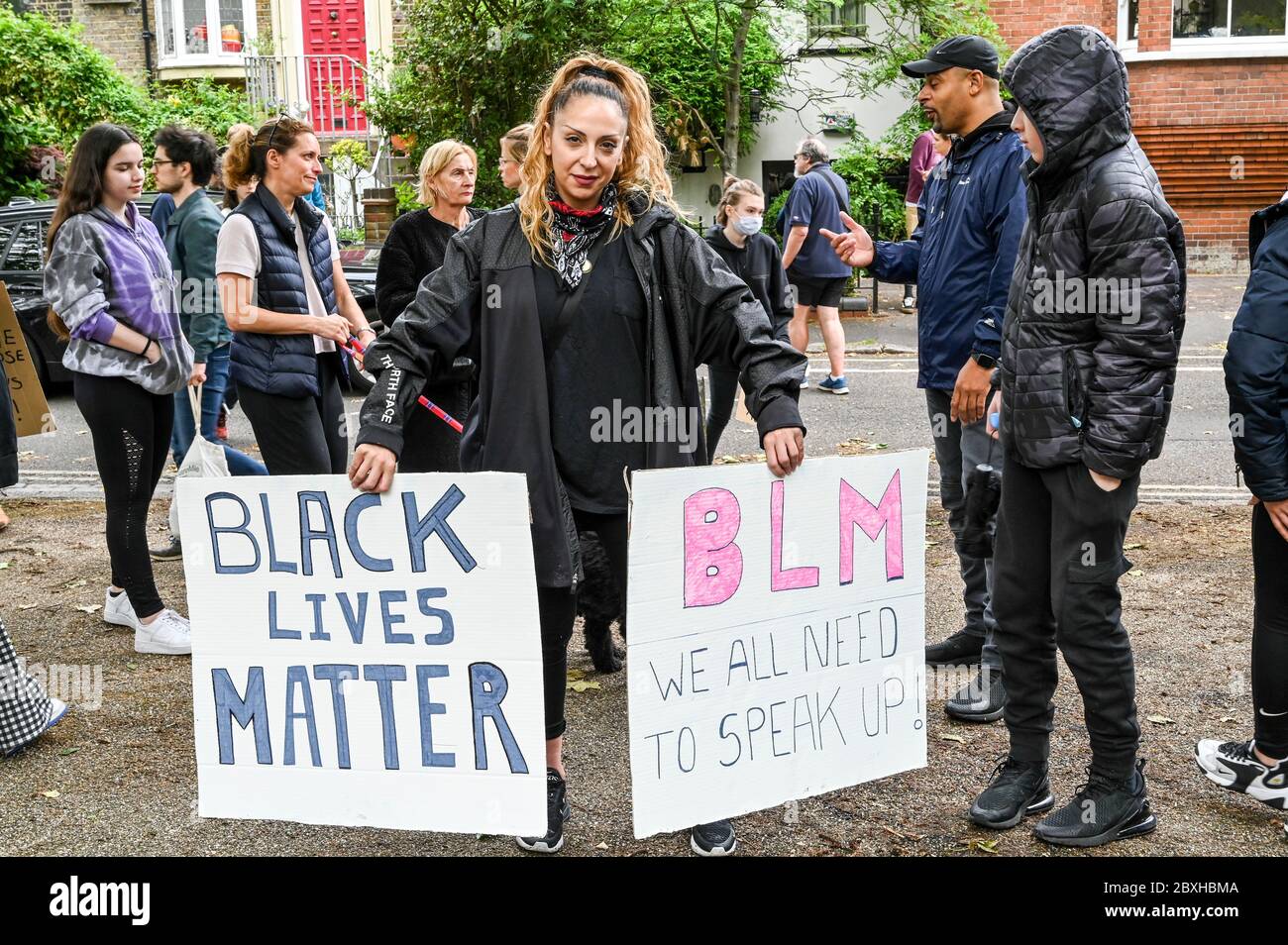 Donna mista con due cartelli "Black Lives Matter", "BLM abbiamo tutti bisogno di parlare in su" circondato da famiglia e amici in una dimostrazione. Londra. Foto Stock