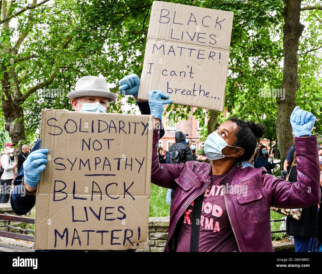 Una coppia di eredità mista in maschere con cartelli 'solidarietà non simpatia' e 'Black Lives Matter; i CAN't breathe' in una dimostrazione a Londra UK. Foto Stock