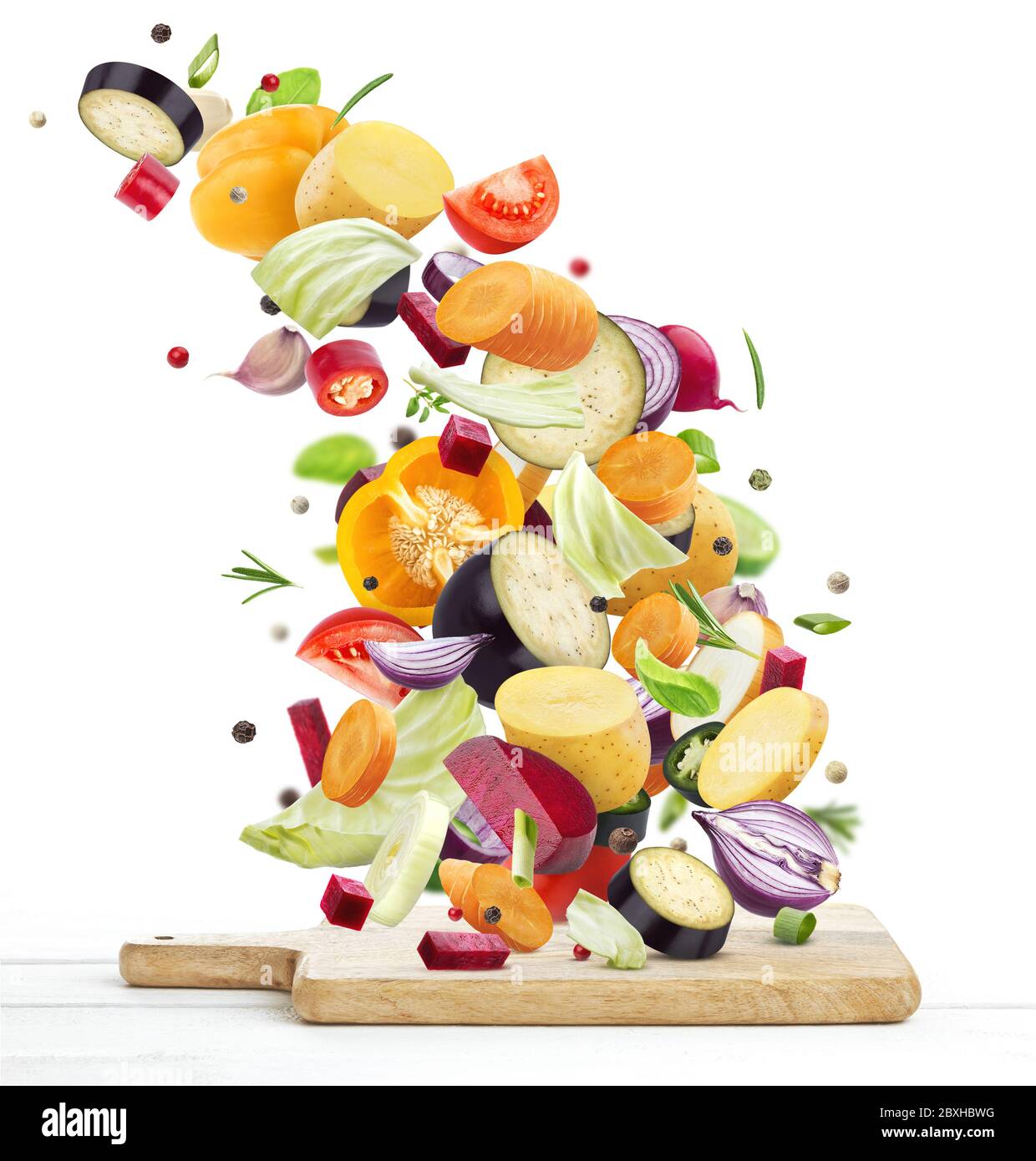 Verdure che cadono su tritare in legno, isolate su sfondo bianco Foto Stock