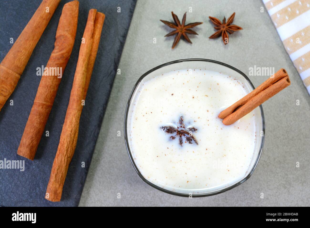 Latte caldo alla cannella in una tazza di vetro guarnita con anice stellato Foto Stock