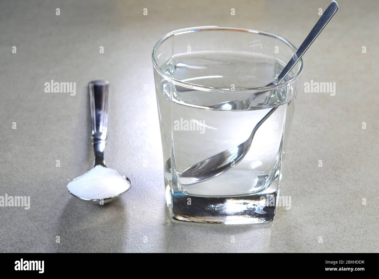 Salare l'acqua in una tazza di vetro e sale in un cucchiaino Foto Stock