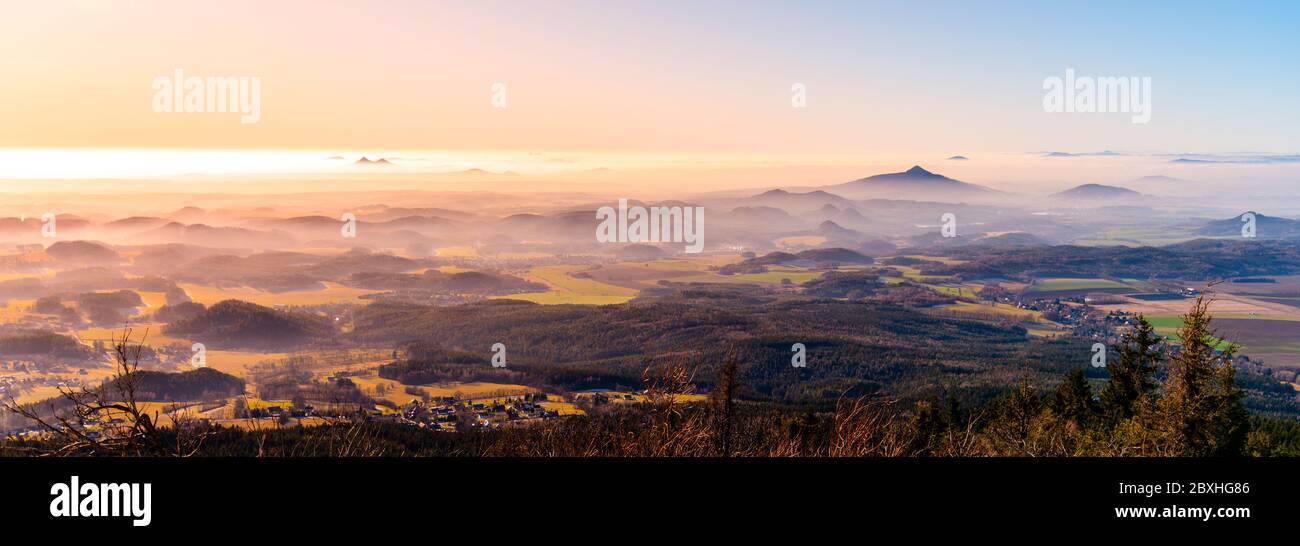 Paesaggio collinare in giornata soleggiata e nebbiosa. Inversione del tempo. Highlands Bohemien centrali, ceco: Ceske stredohori, Repubblica Ceca. Foto Stock