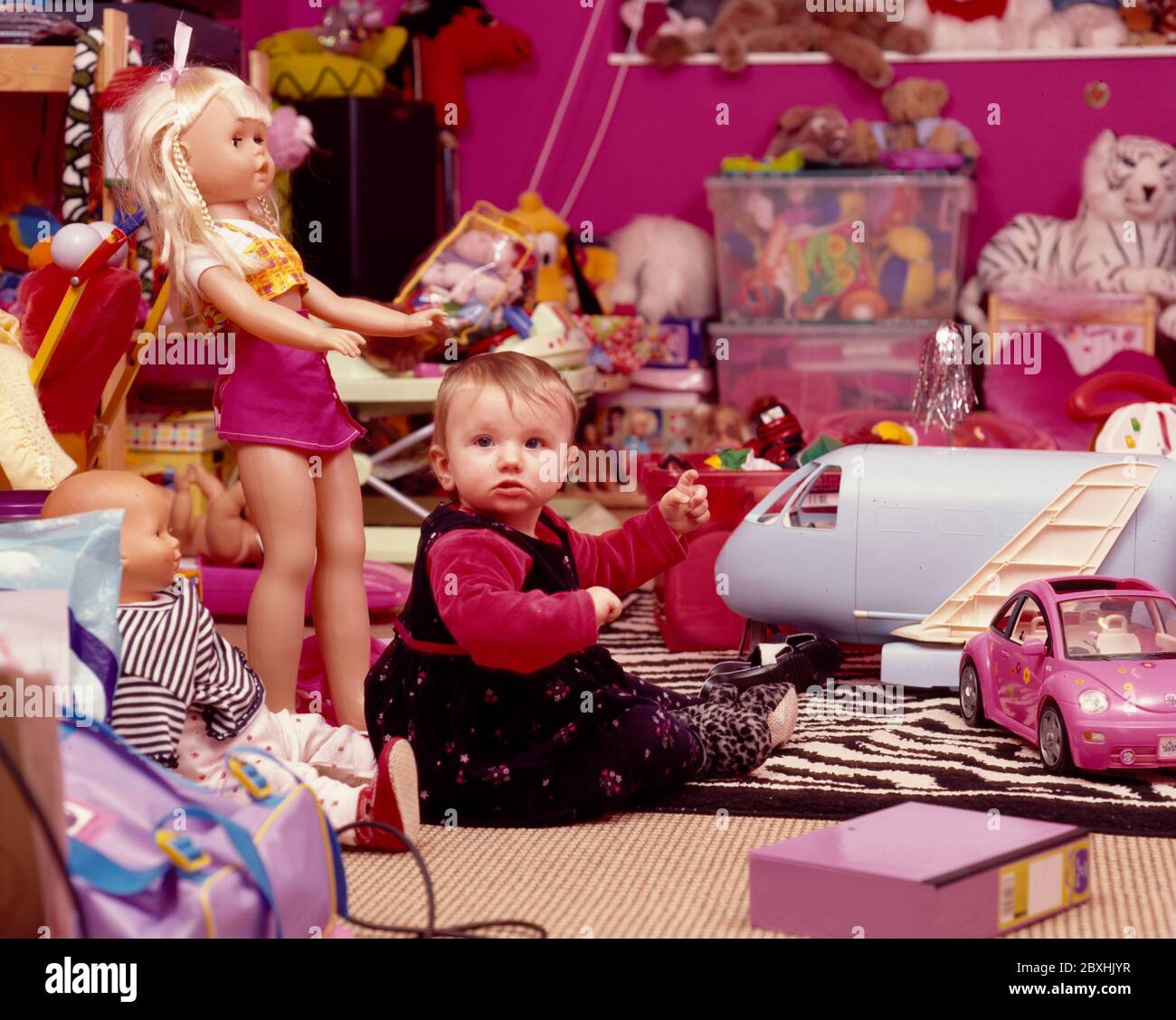 Un bambino di un anno in sala giochi circondata da giocattoli Foto Stock
