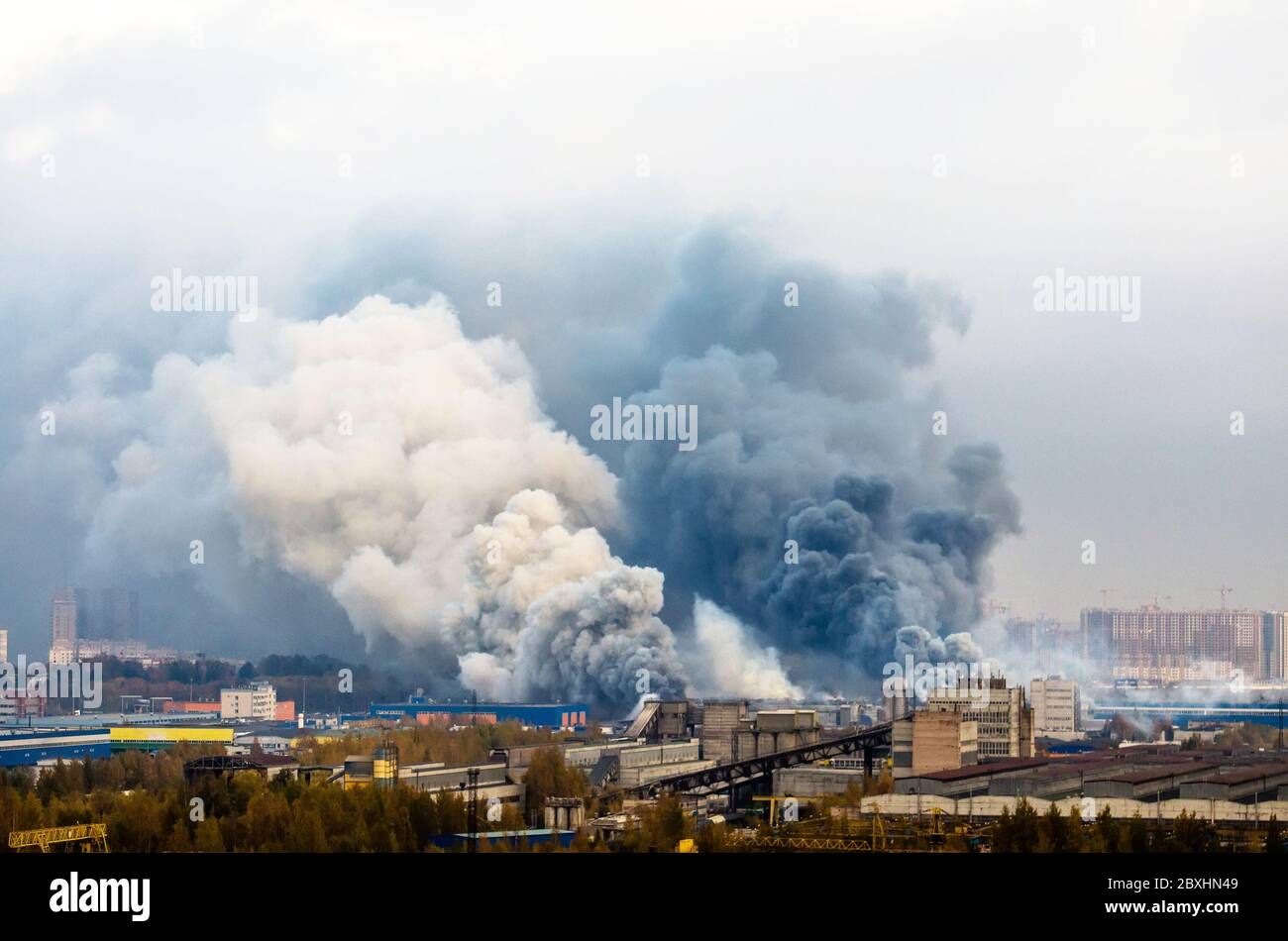 Incendio in magazzini con enormi nuvole di fumo scure e bianche Foto Stock