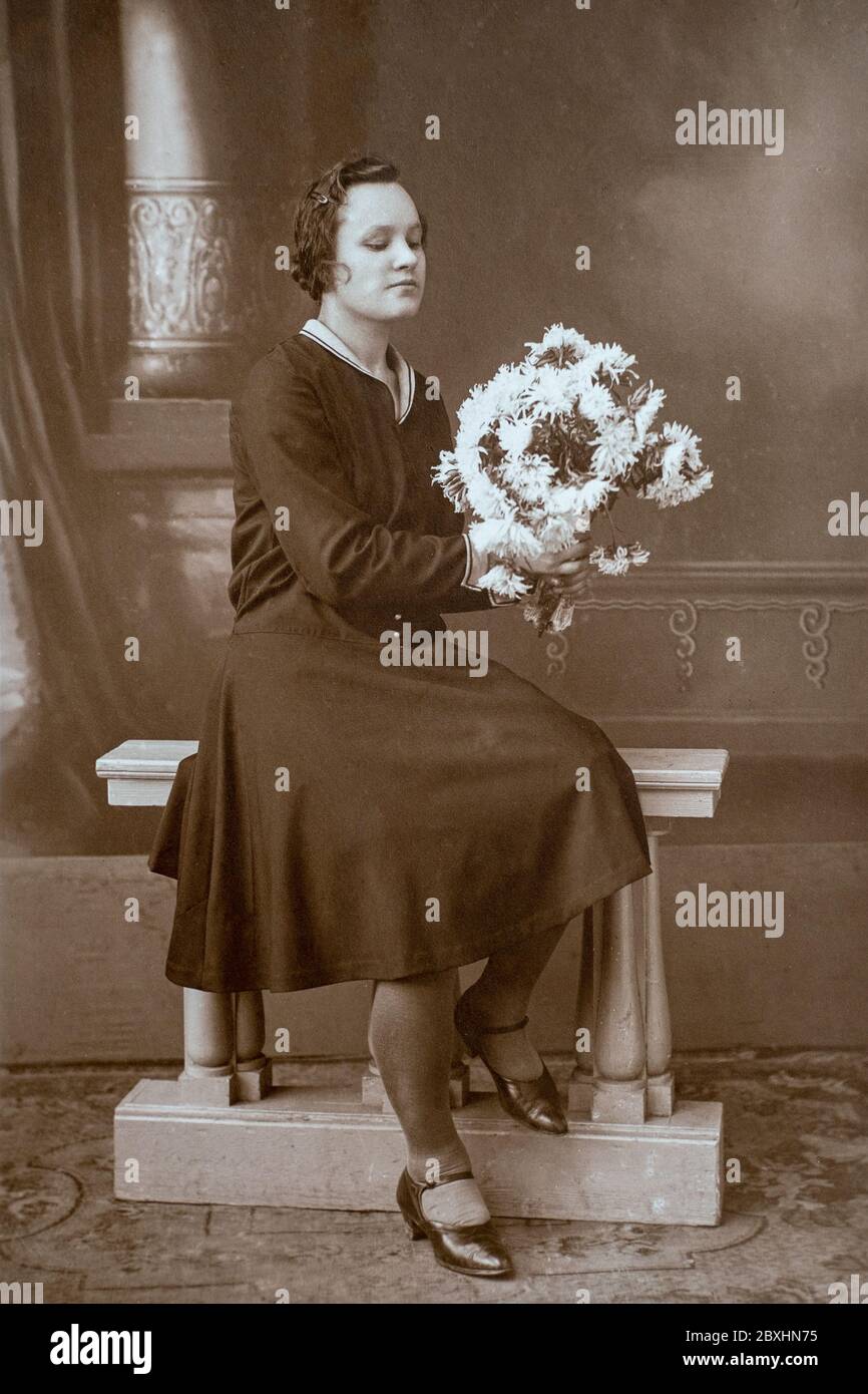 Germania - CIRCA anni '30: Ritratto di giovane donna seduta alla panchina in studio, vintage carte de Viste Art Deco era foto Foto Stock