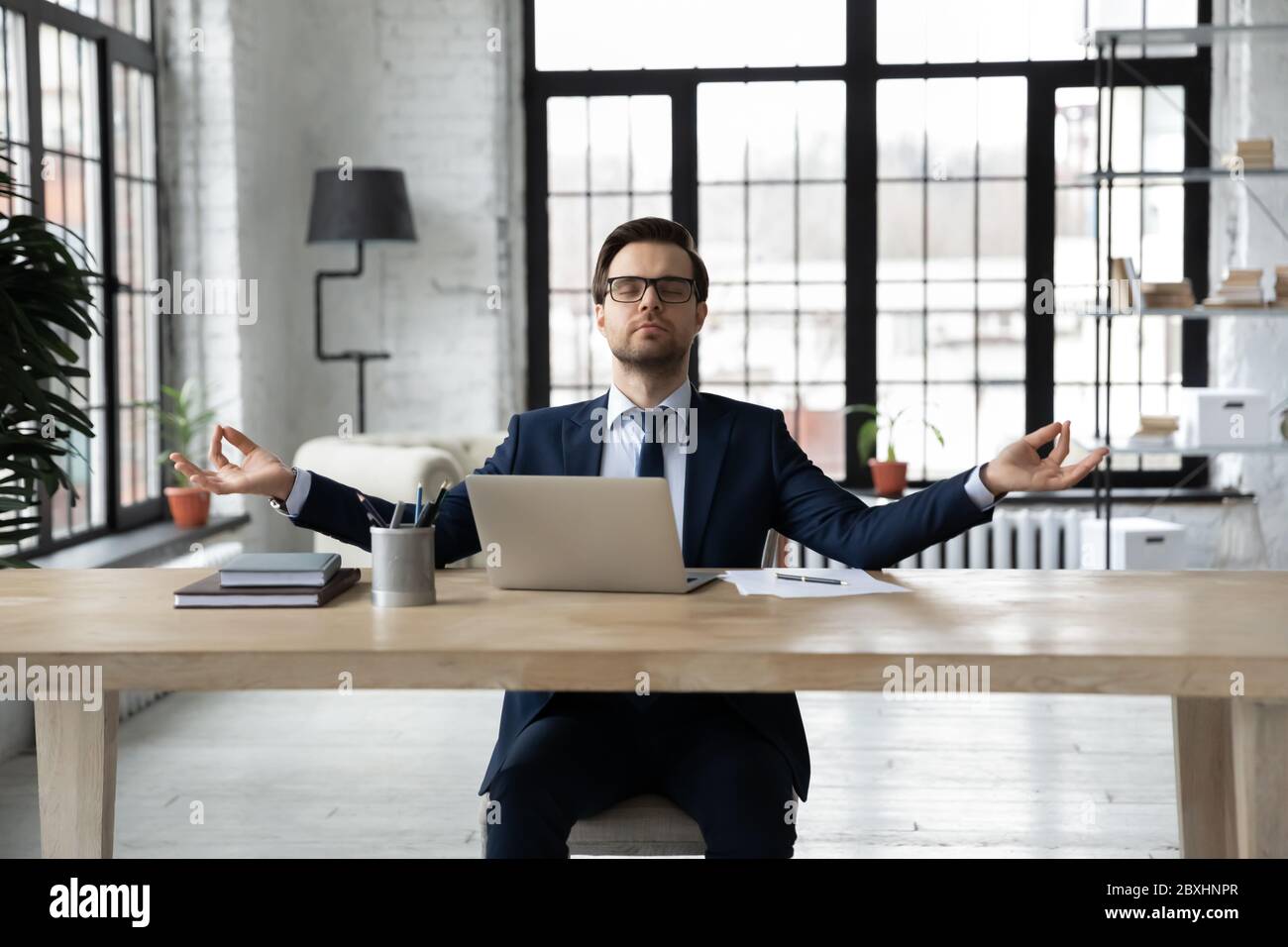 Uomo d'affari calmo pratica yoga alla scrivania in ufficio Foto Stock